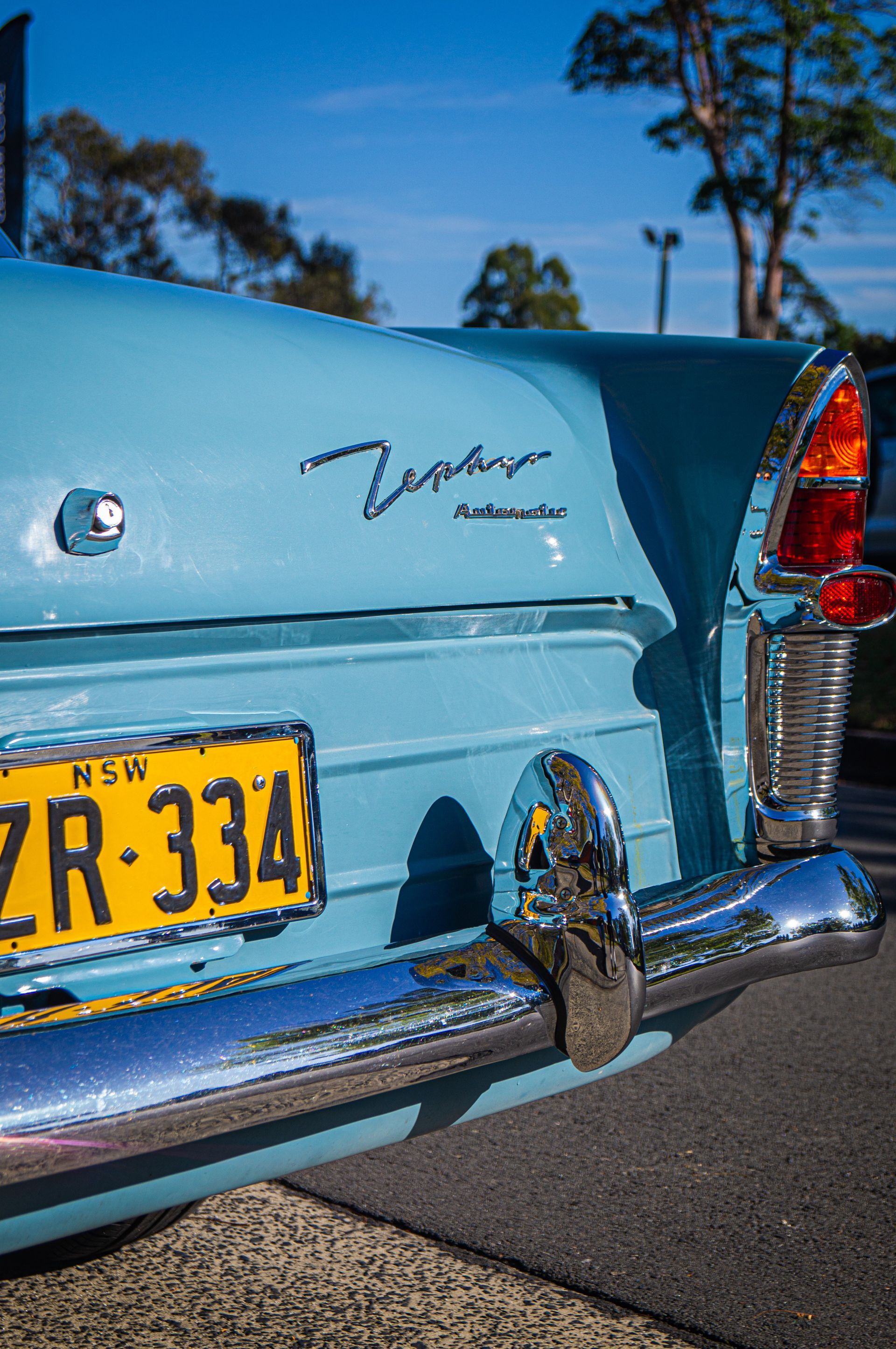 A blue car with a license plate that says zr 334 is parked on the side of the road.