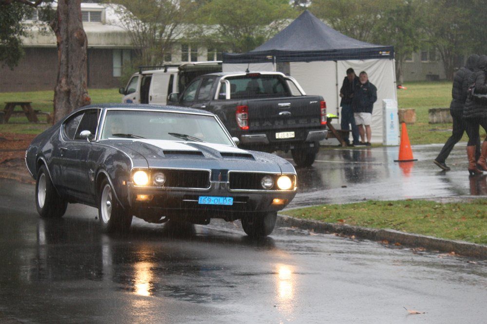 A car is driving down a wet street in the rain.