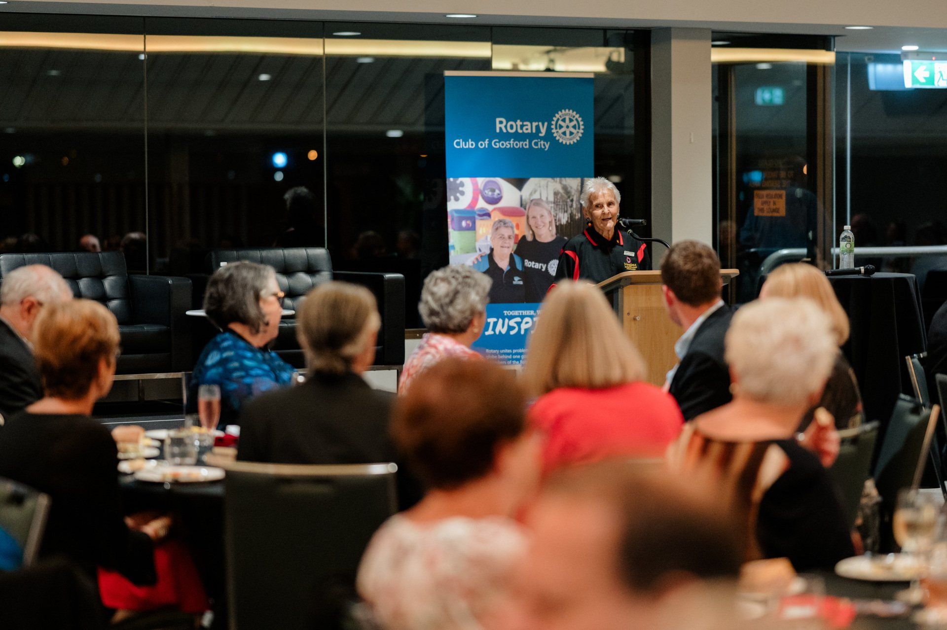 A man is giving a speech to a group of people sitting at tables.