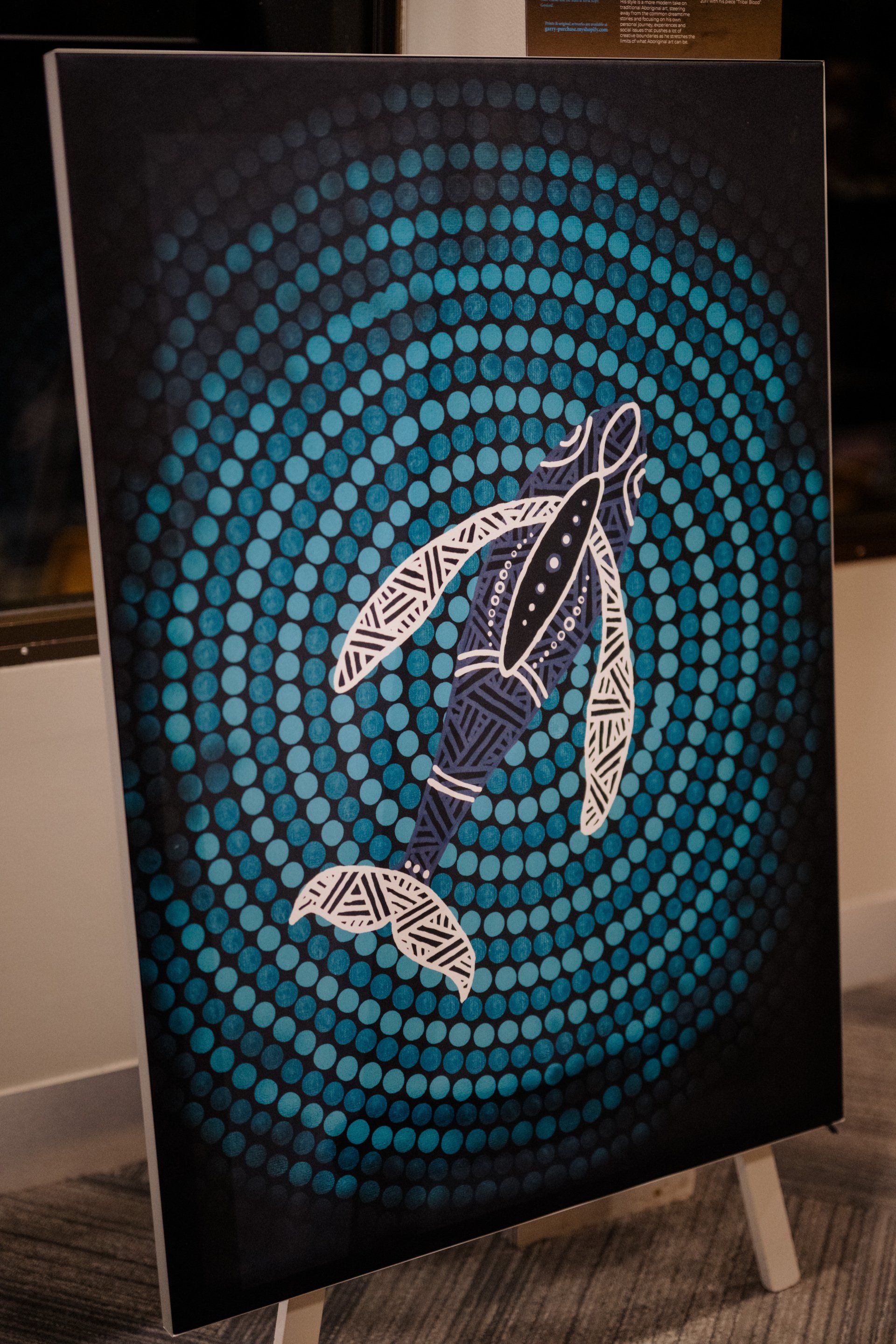 A painting of a whale is sitting on a wooden easel.