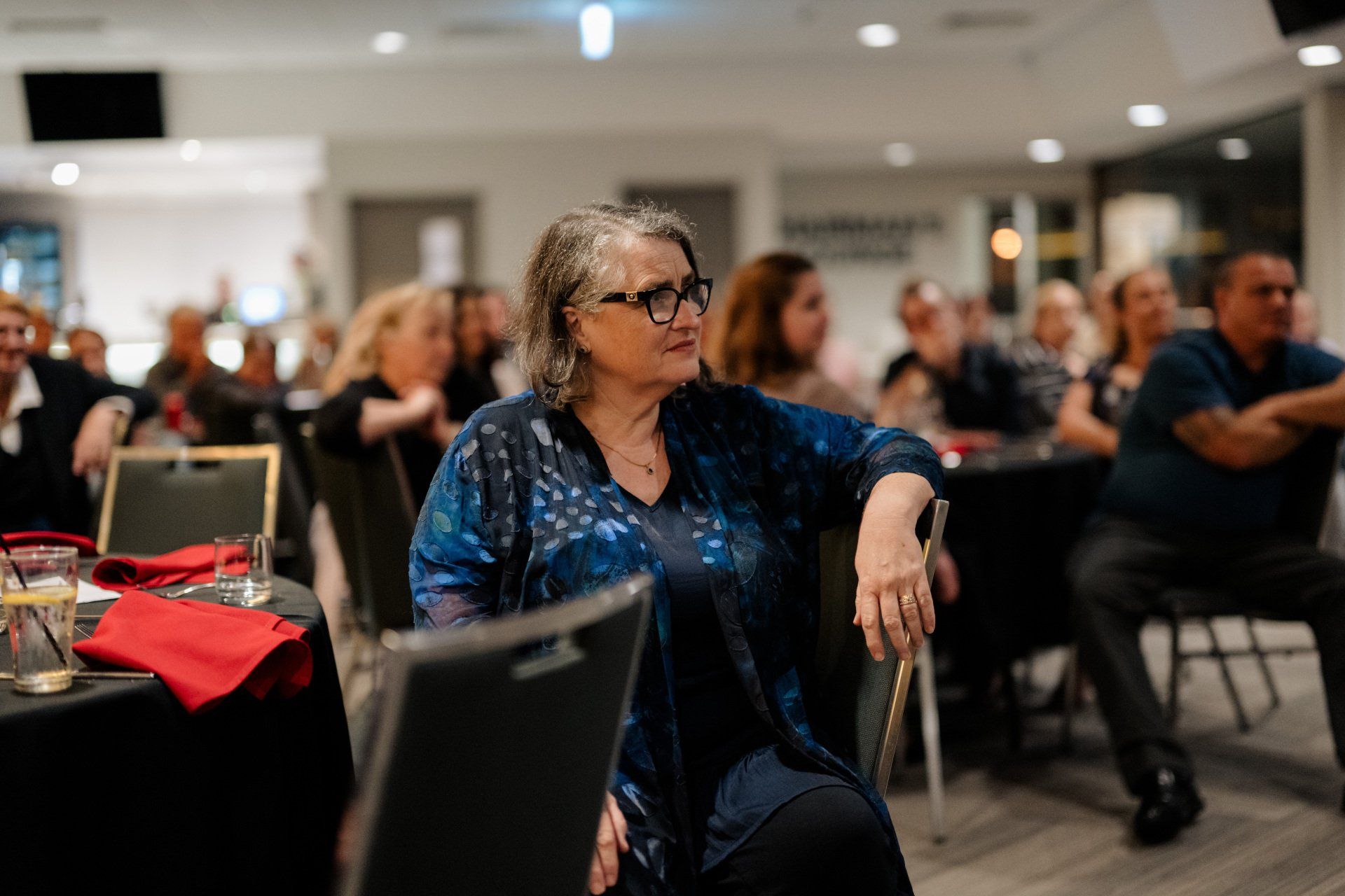 A woman is sitting in a chair with a cane at a party.