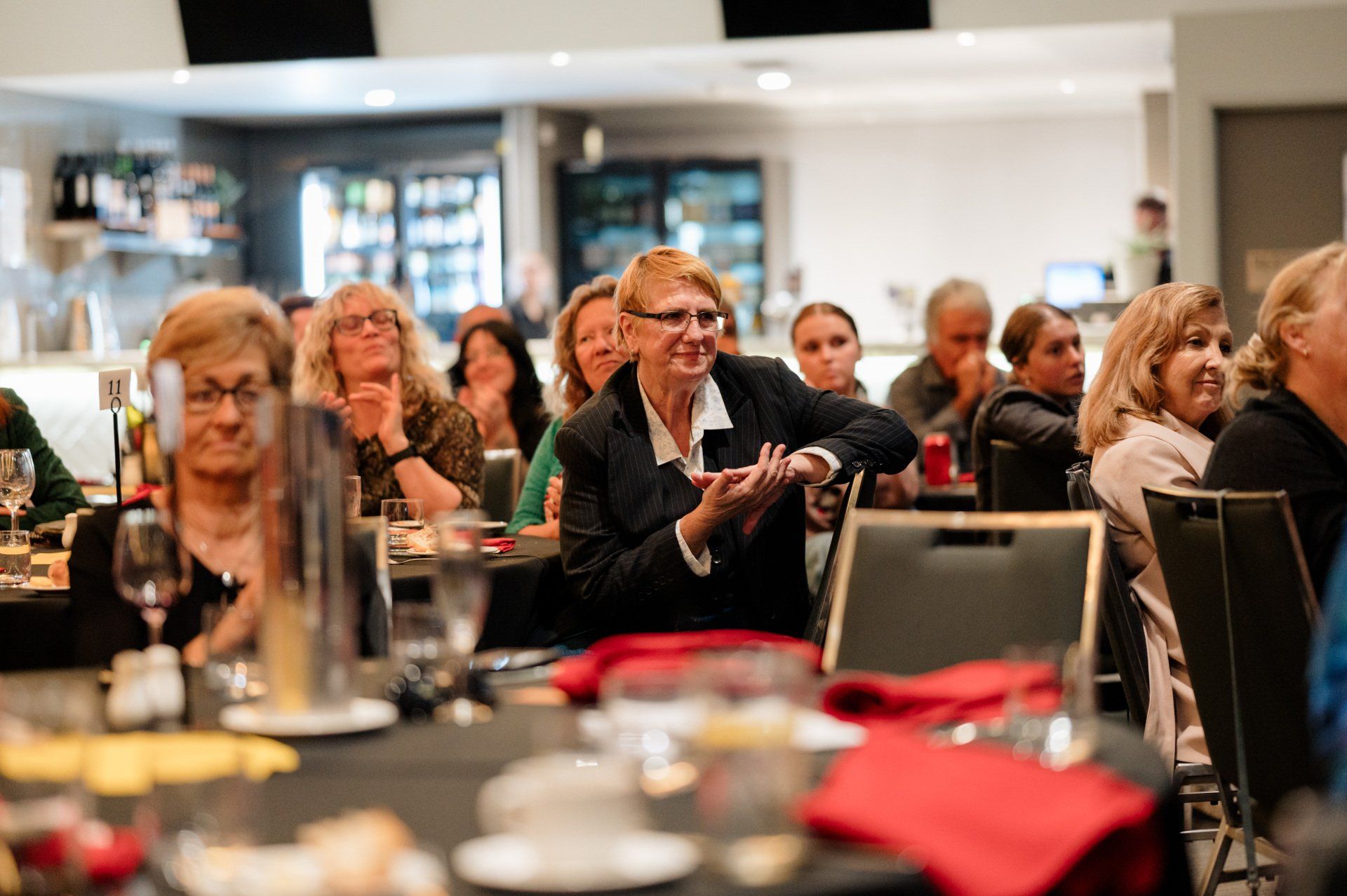 A group of people are sitting at tables in a room applauding.