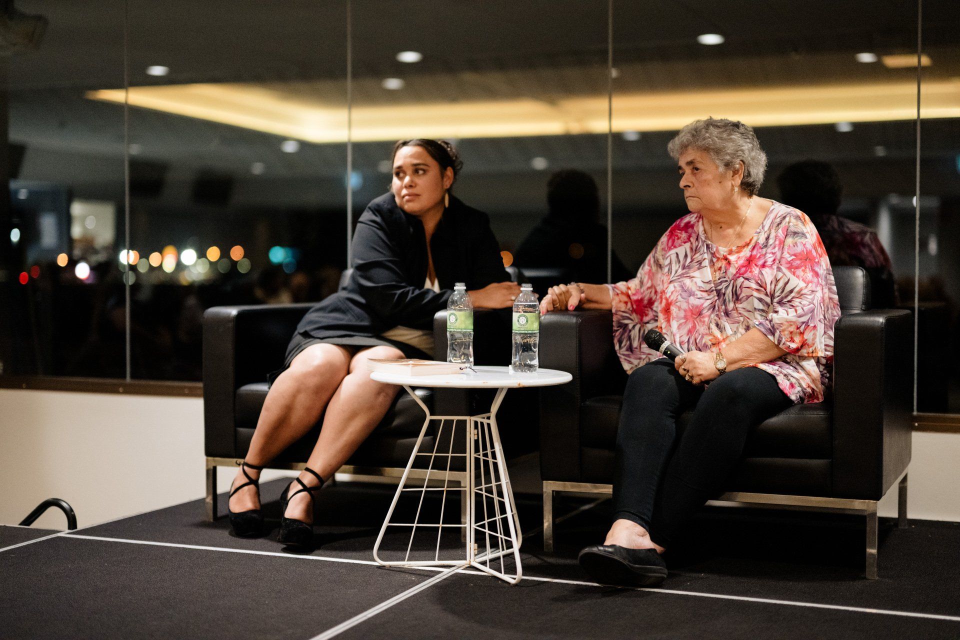 Two women are sitting in chairs talking to each other.