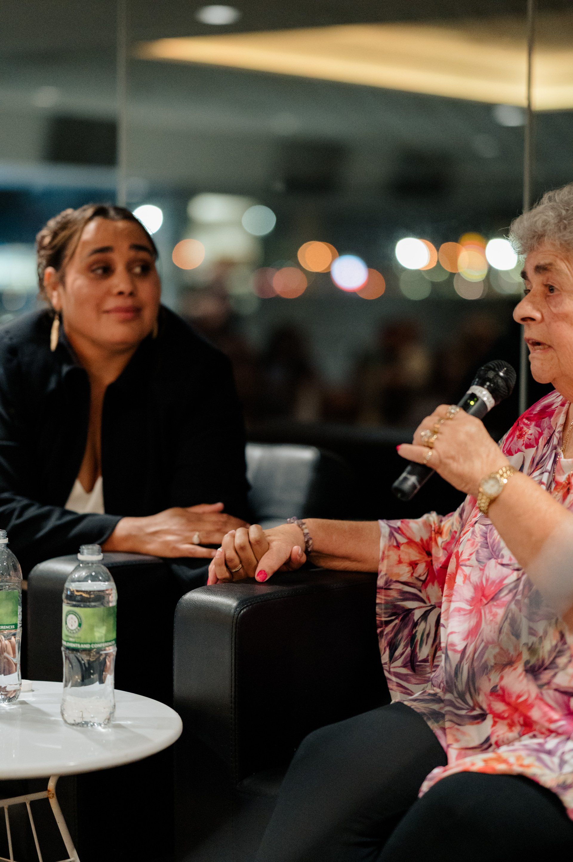 Two women are sitting at a table talking into a microphone.