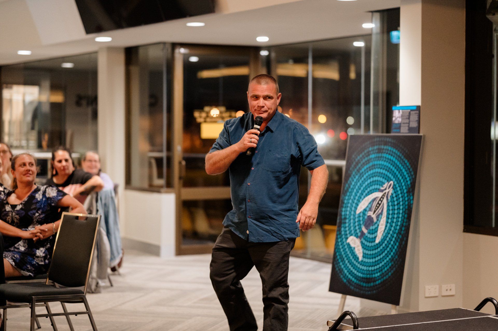 A man is standing in front of a microphone in a room.