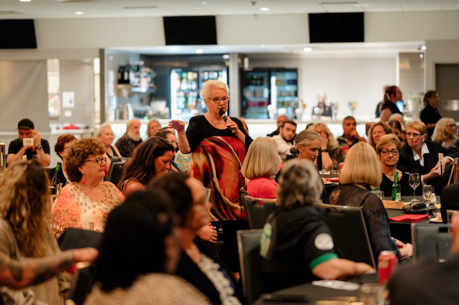 A woman is standing in front of a crowd of people at a conference.