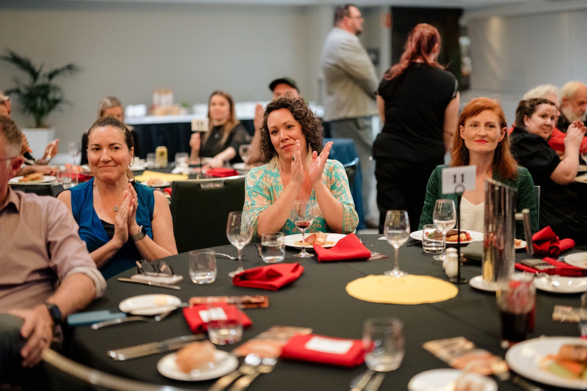 A group of people are sitting at a table clapping.