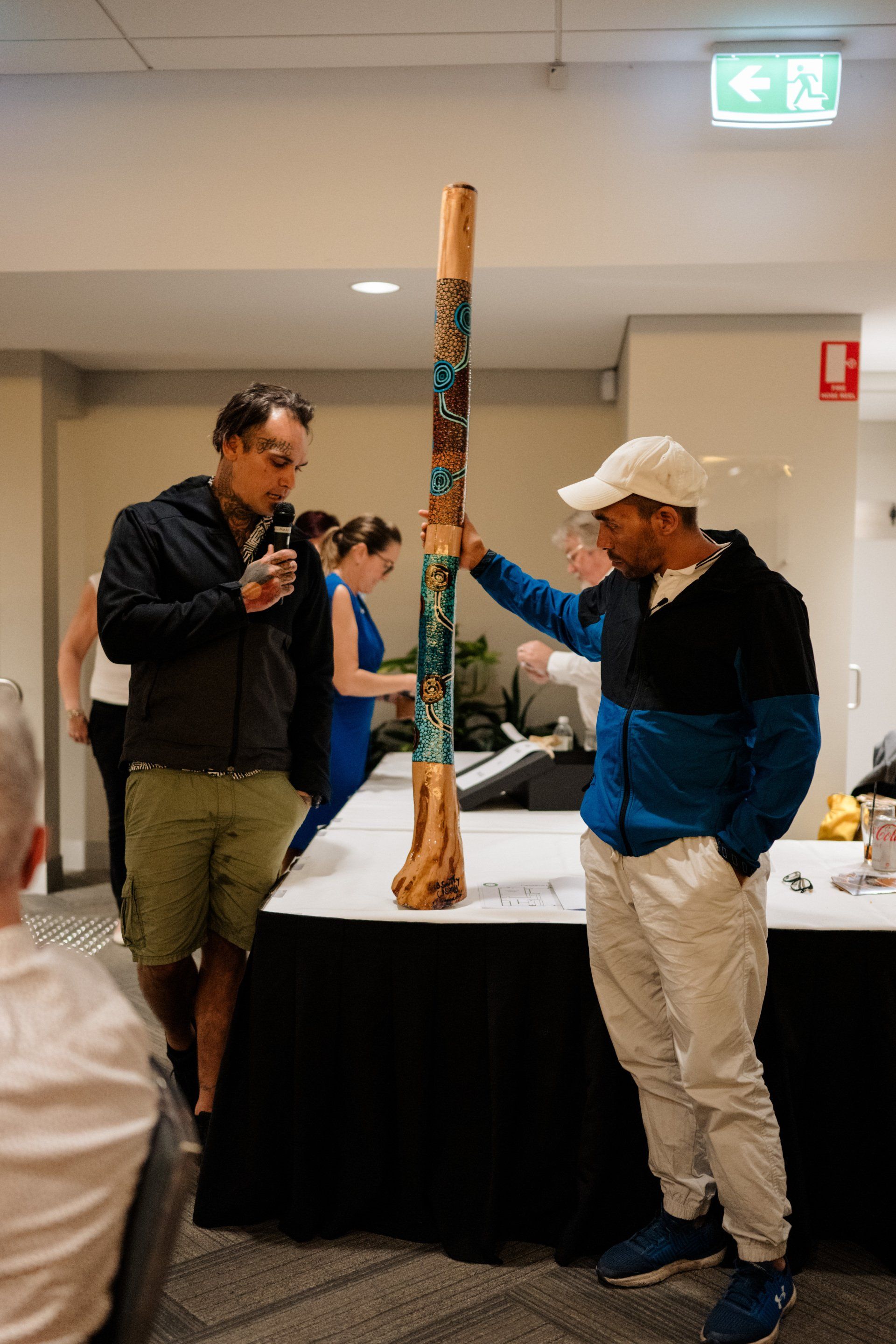 Two men are standing next to each other in a room holding a sculpture.