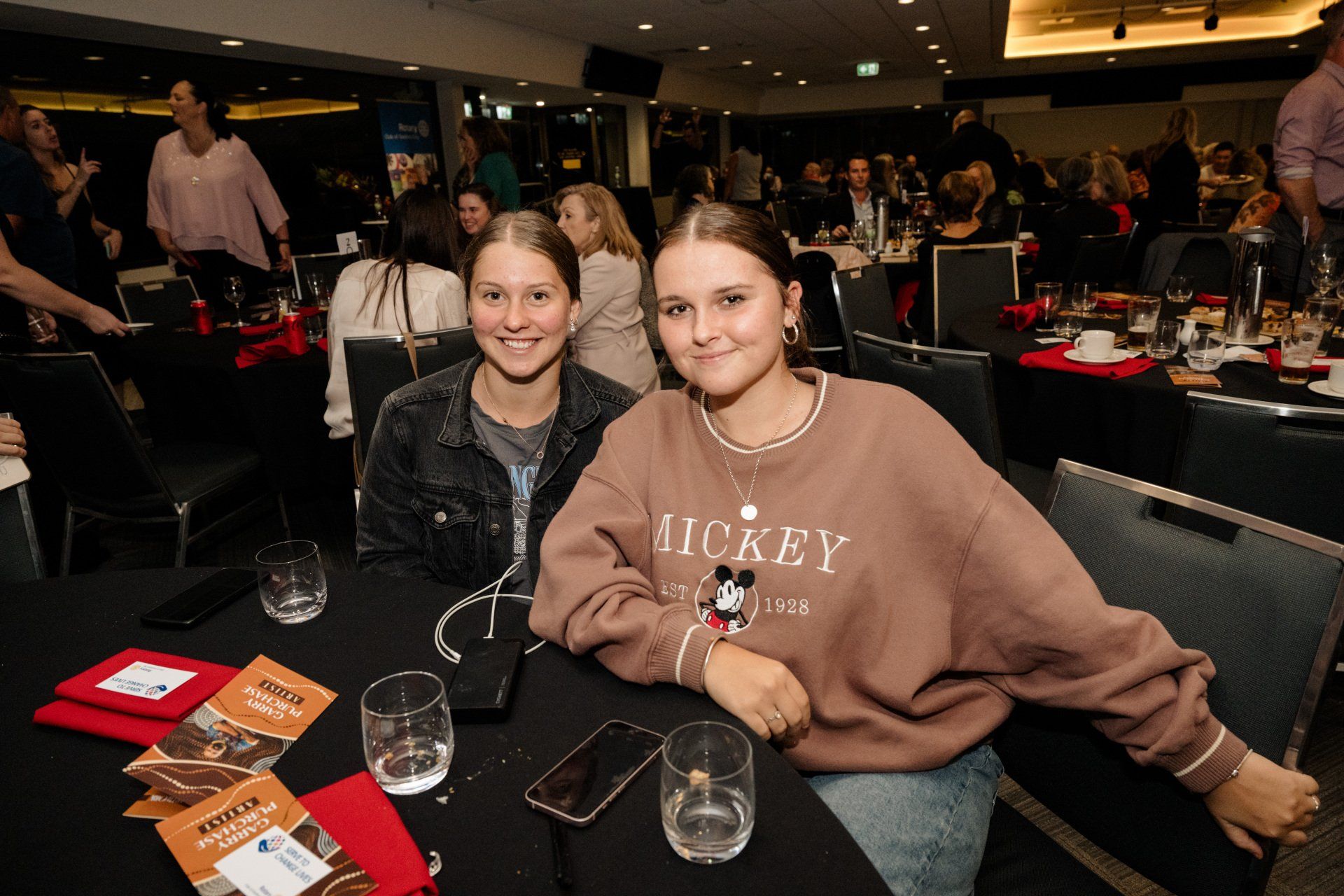 Two girls are sitting at a table at a party.