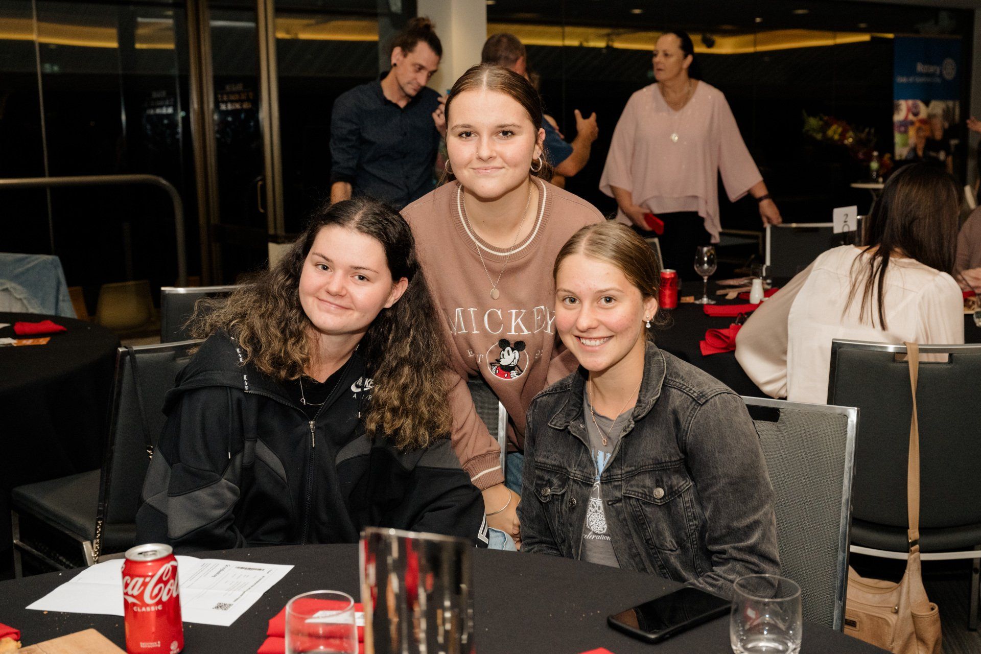 A group of young women are posing for a picture at a table.