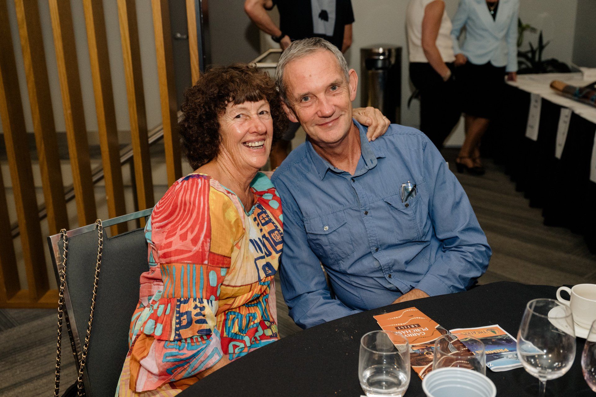 A man and a woman are sitting at a table with wine glasses.