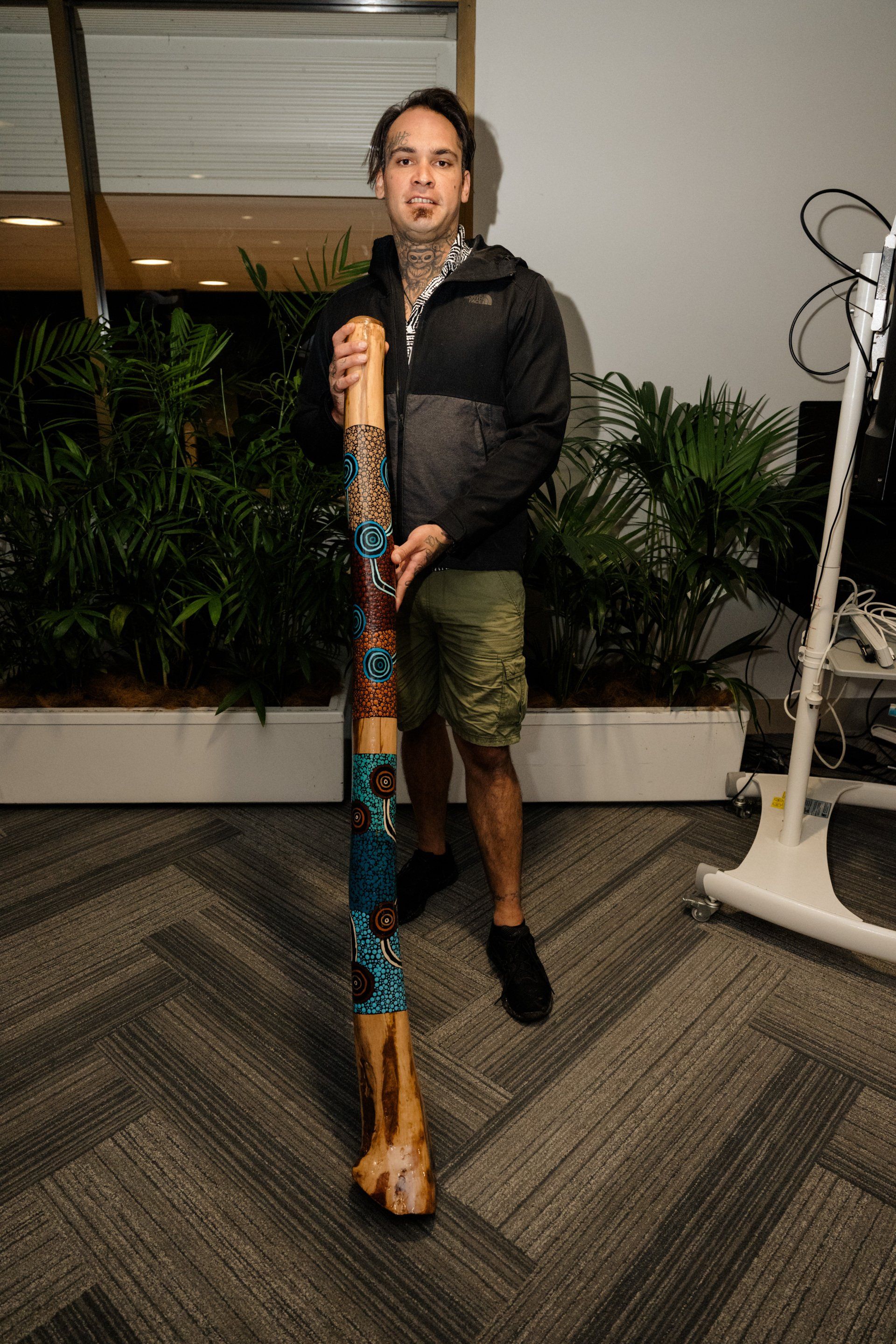 A man is holding a long wooden stick in a room.
