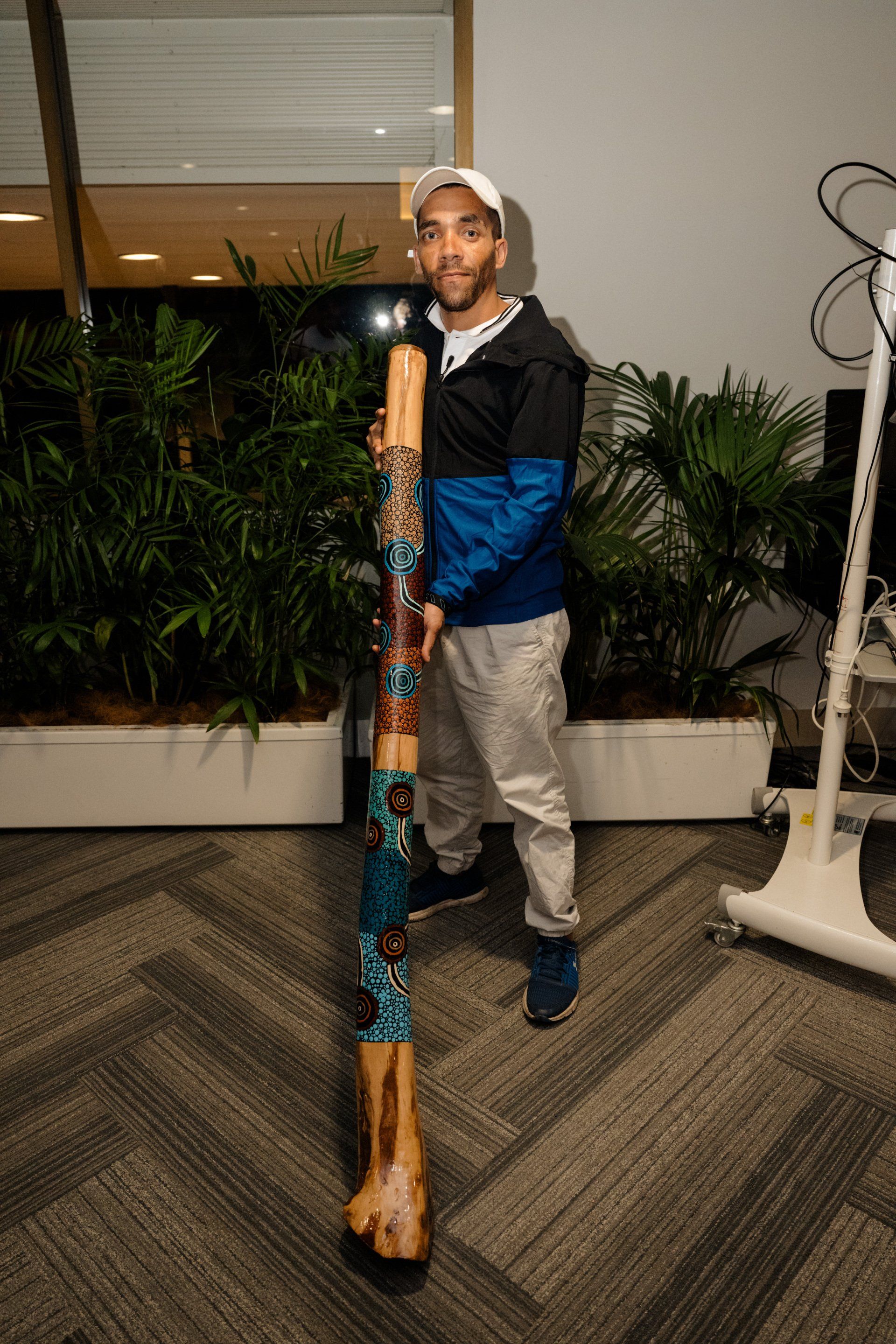 A man is holding a long wooden stick in a room.