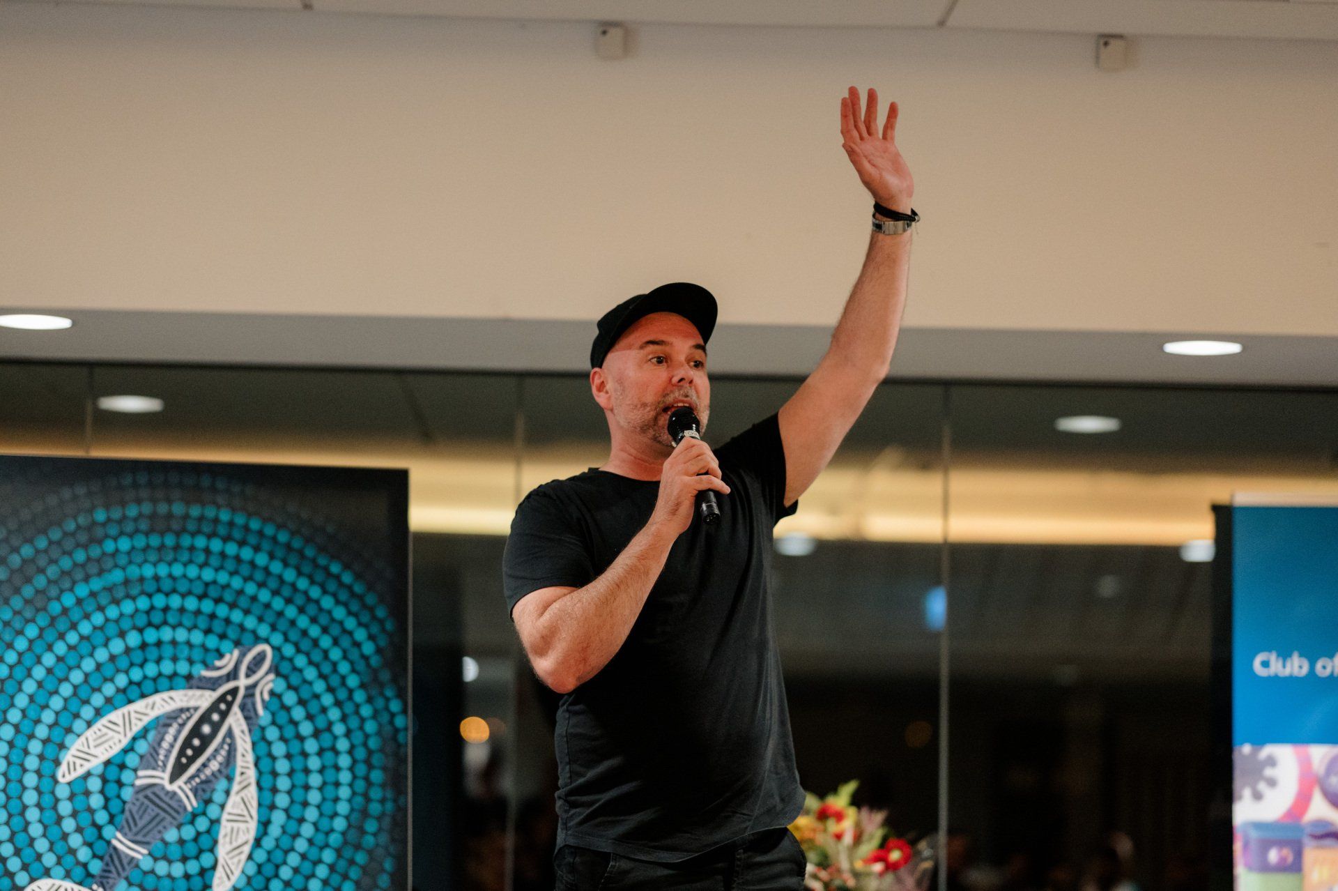 A man is standing in front of a microphone with his hand in the air.