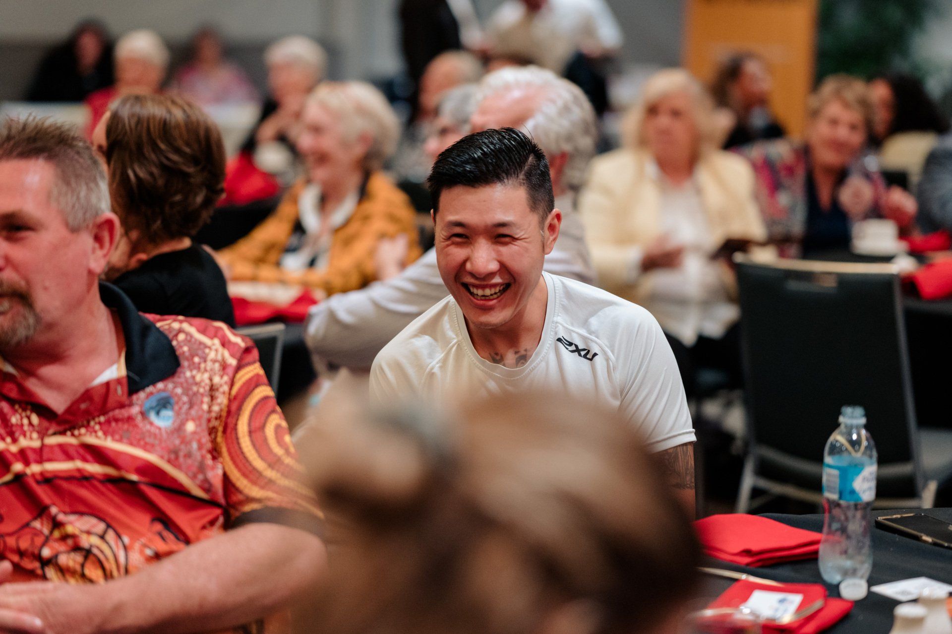 A group of people are sitting at tables in a room and laughing.