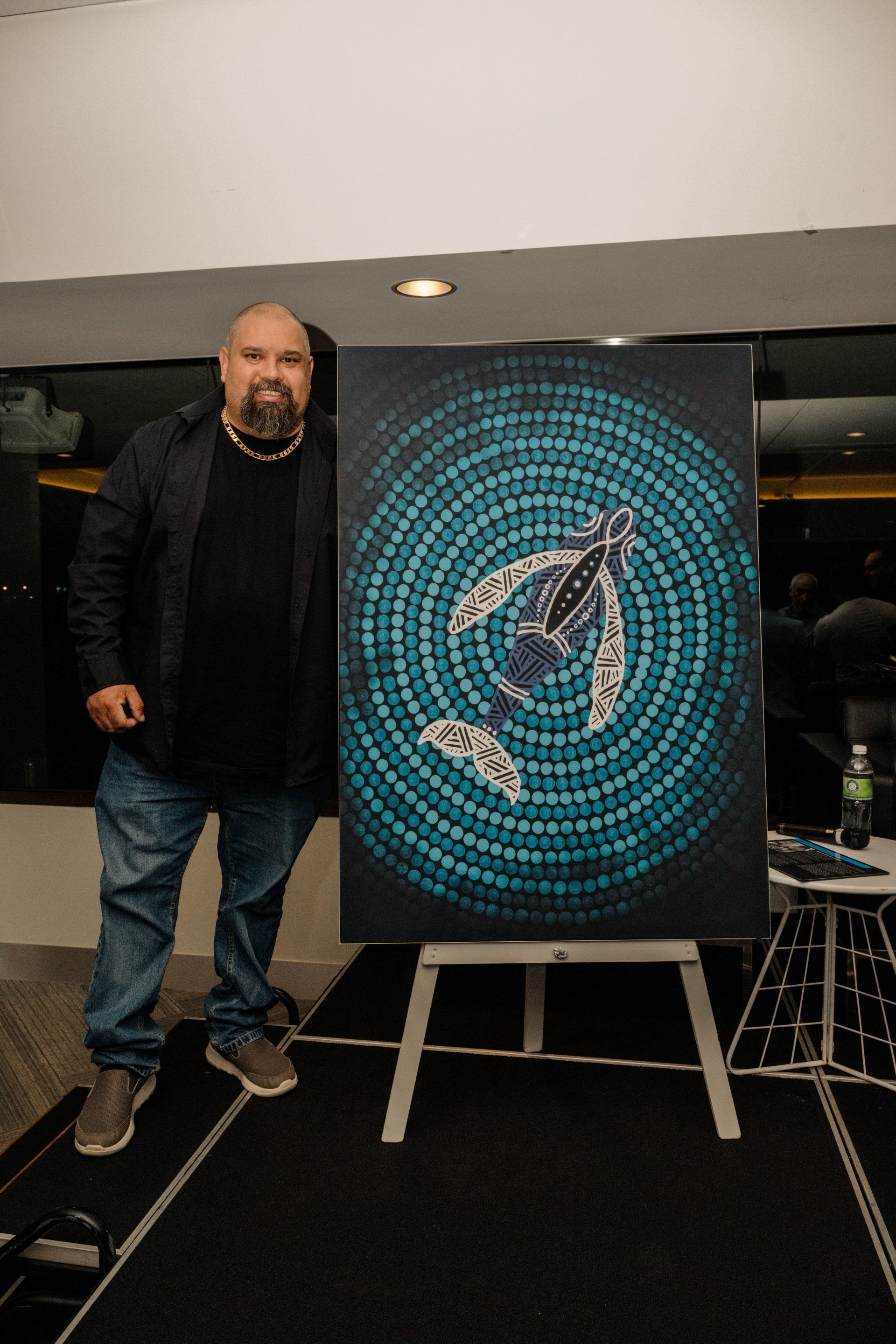 A man is standing next to a painting of a whale on an easel.