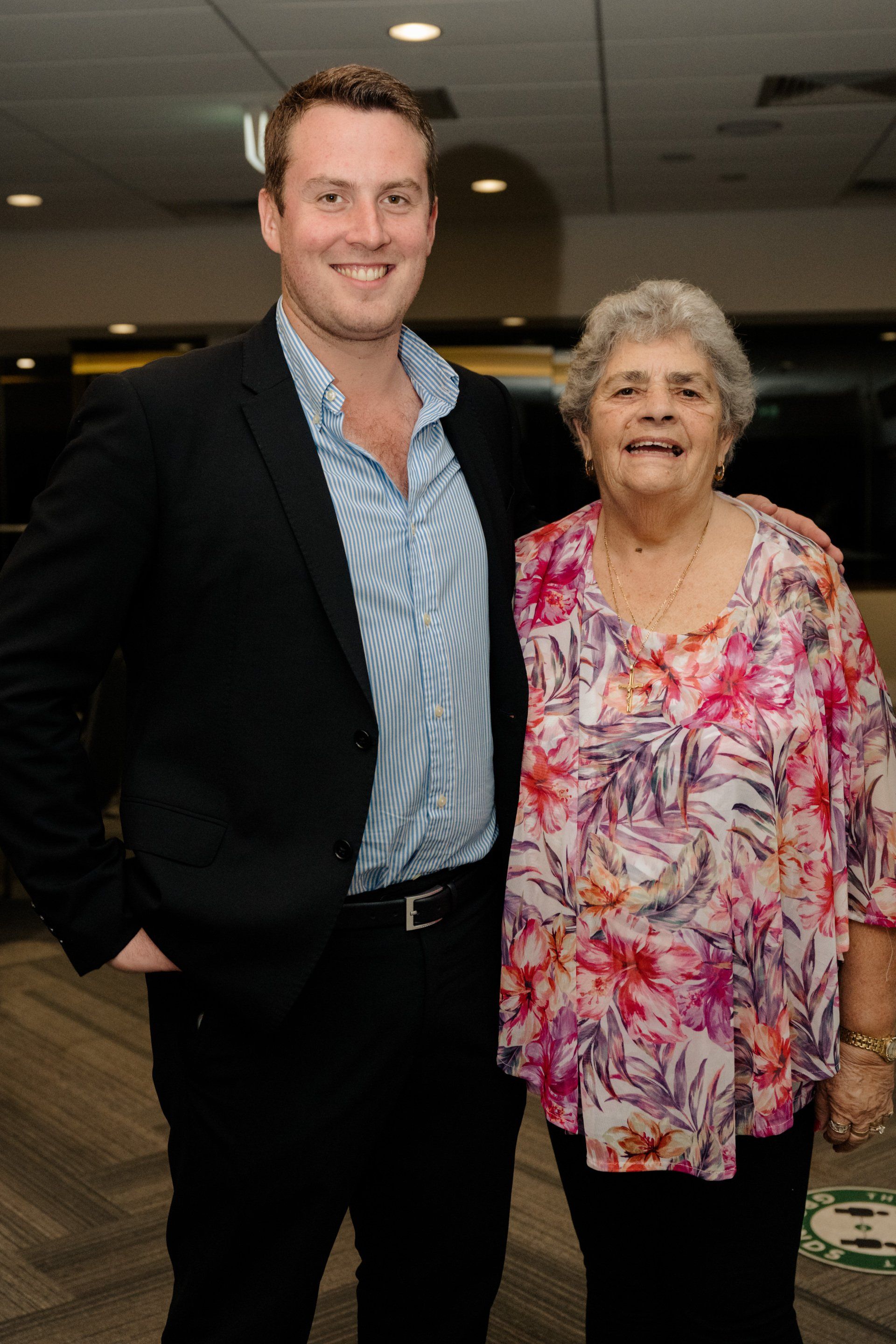 A man in a suit and a woman in a floral shirt are posing for a picture.
