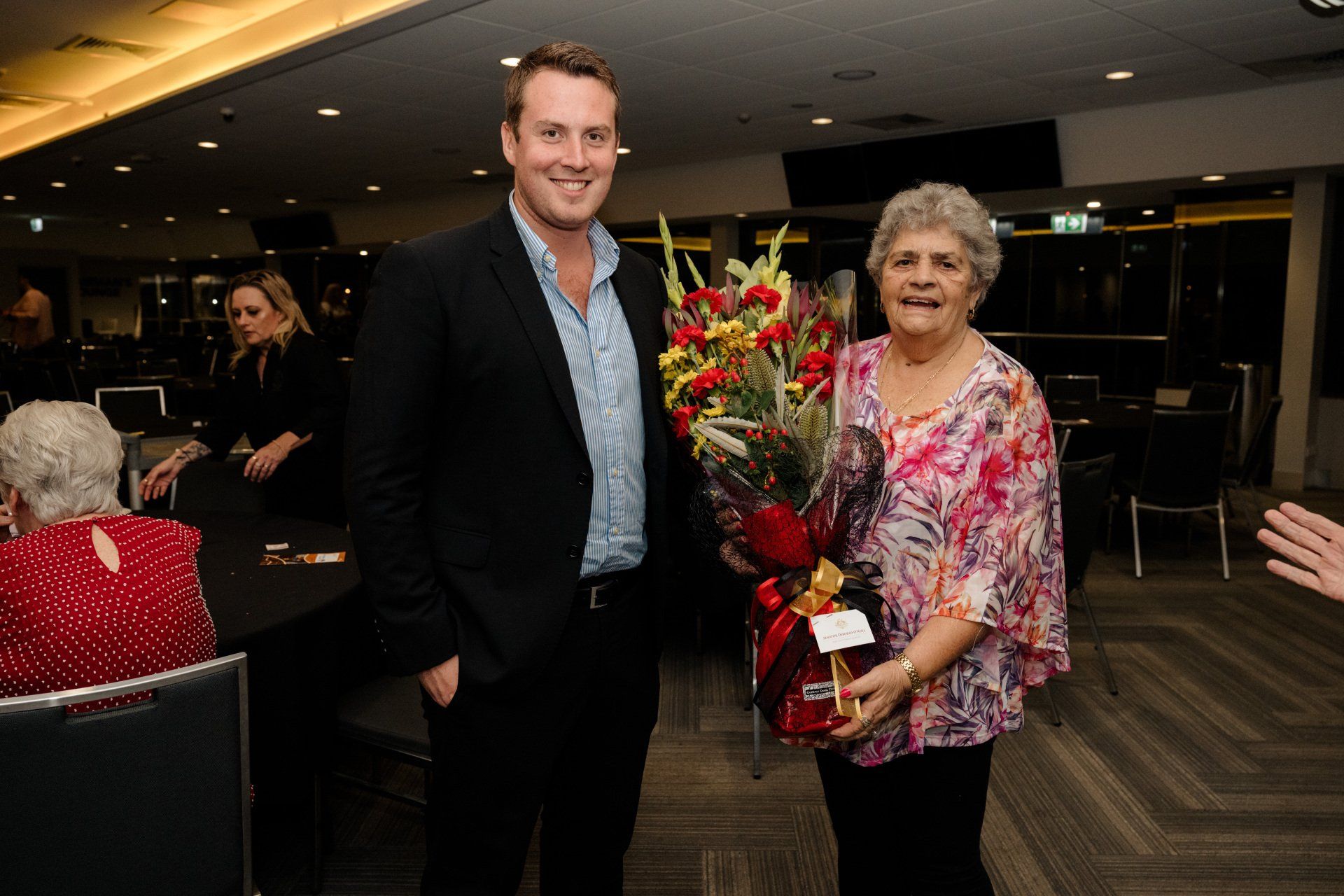 A man in a suit is standing next to a woman holding a bouquet of flowers.