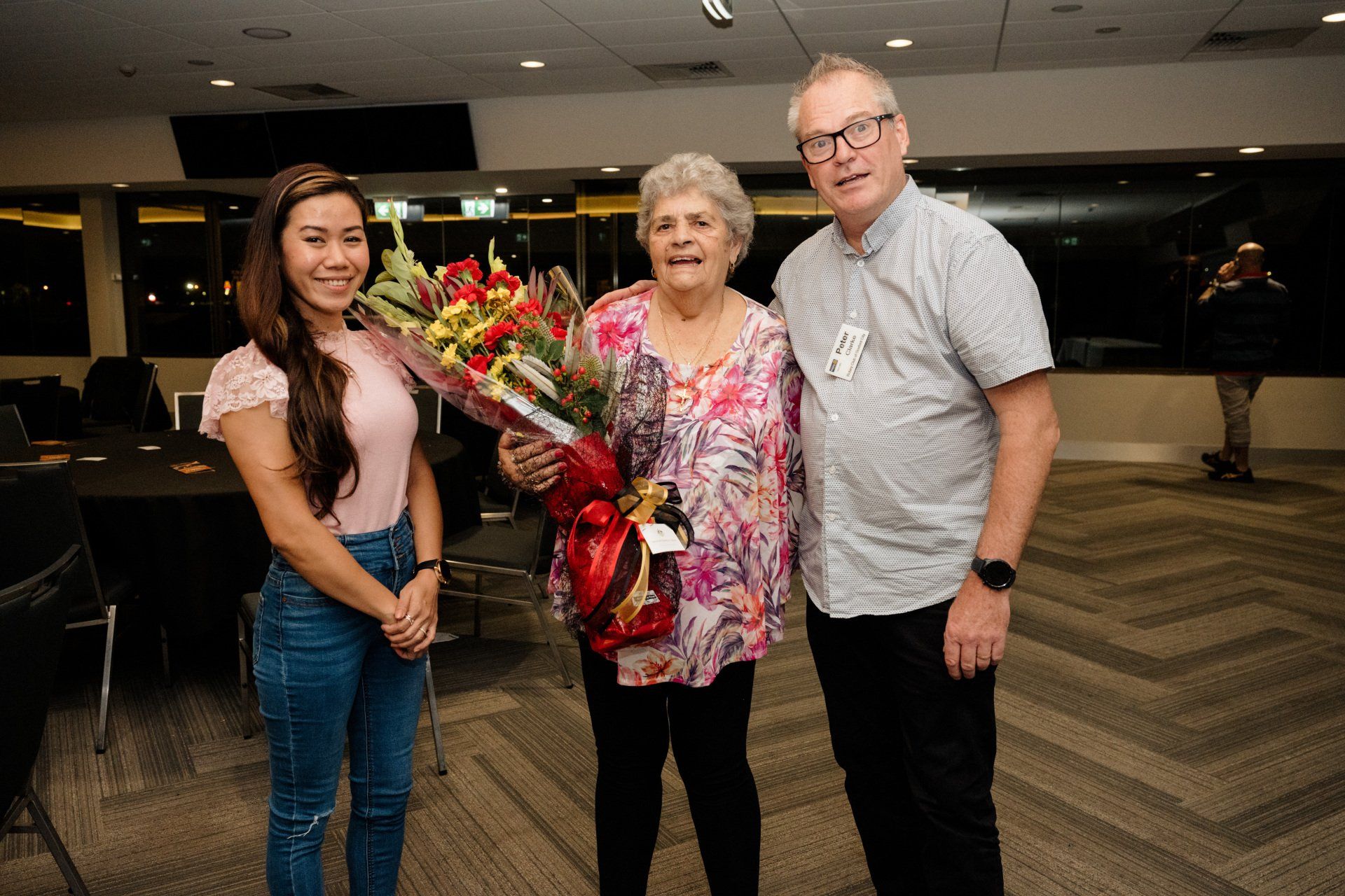 A woman is holding a bouquet of flowers while standing next to a man and a woman.