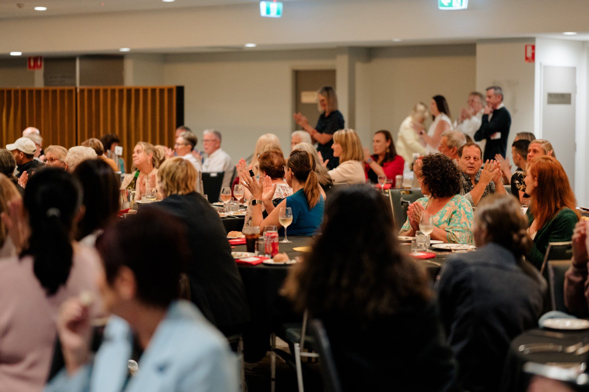 A large group of people are sitting at tables in a room.