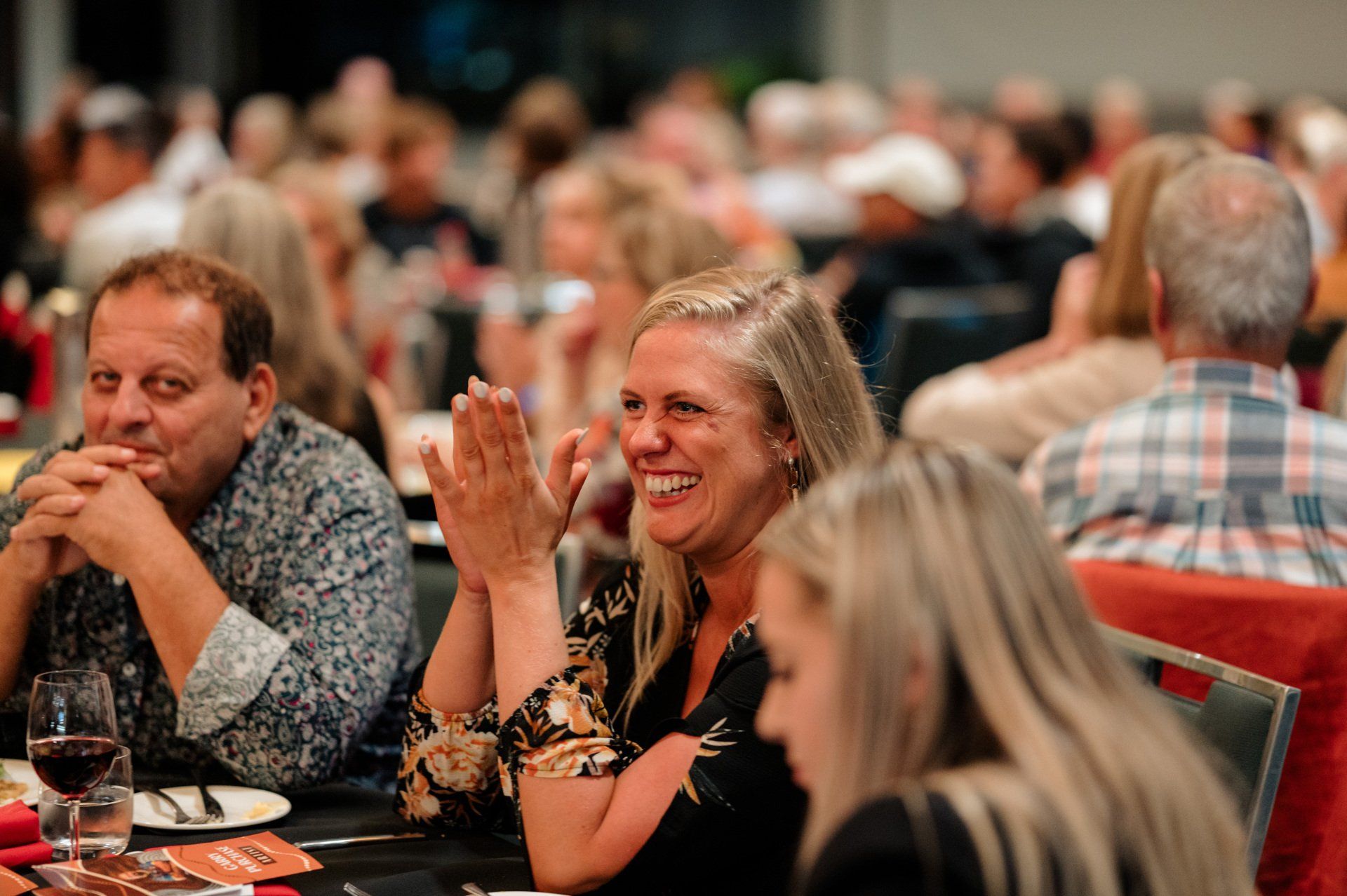A group of people are sitting at a table clapping their hands.