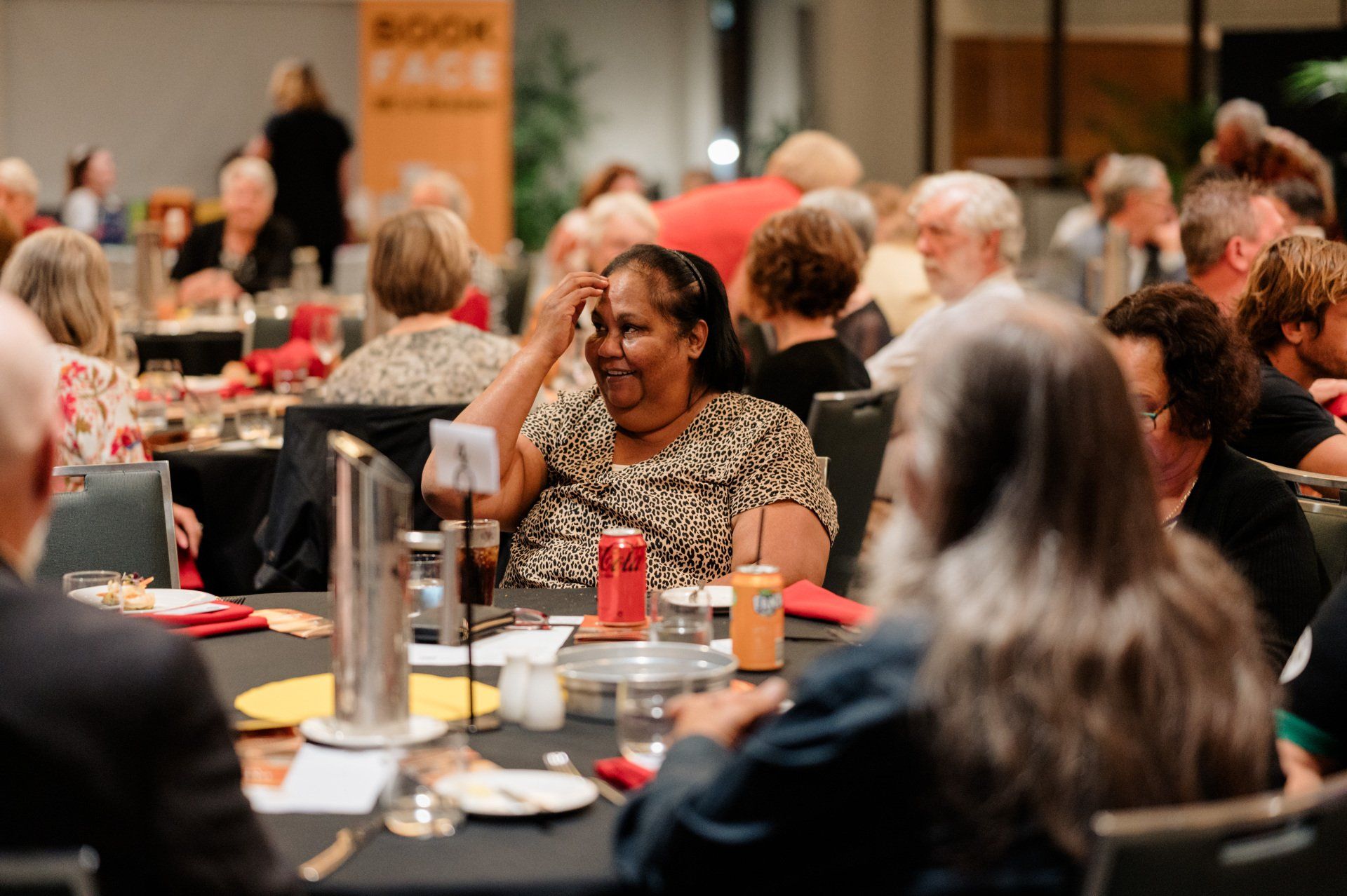 A group of people are sitting at tables at a dinner party.