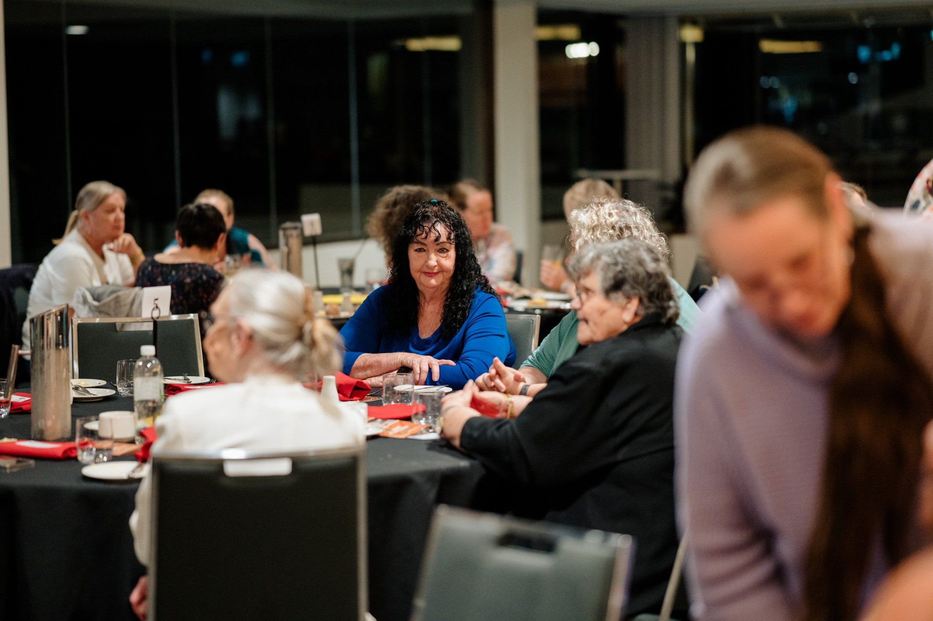 A group of people are sitting at tables at a dinner party.