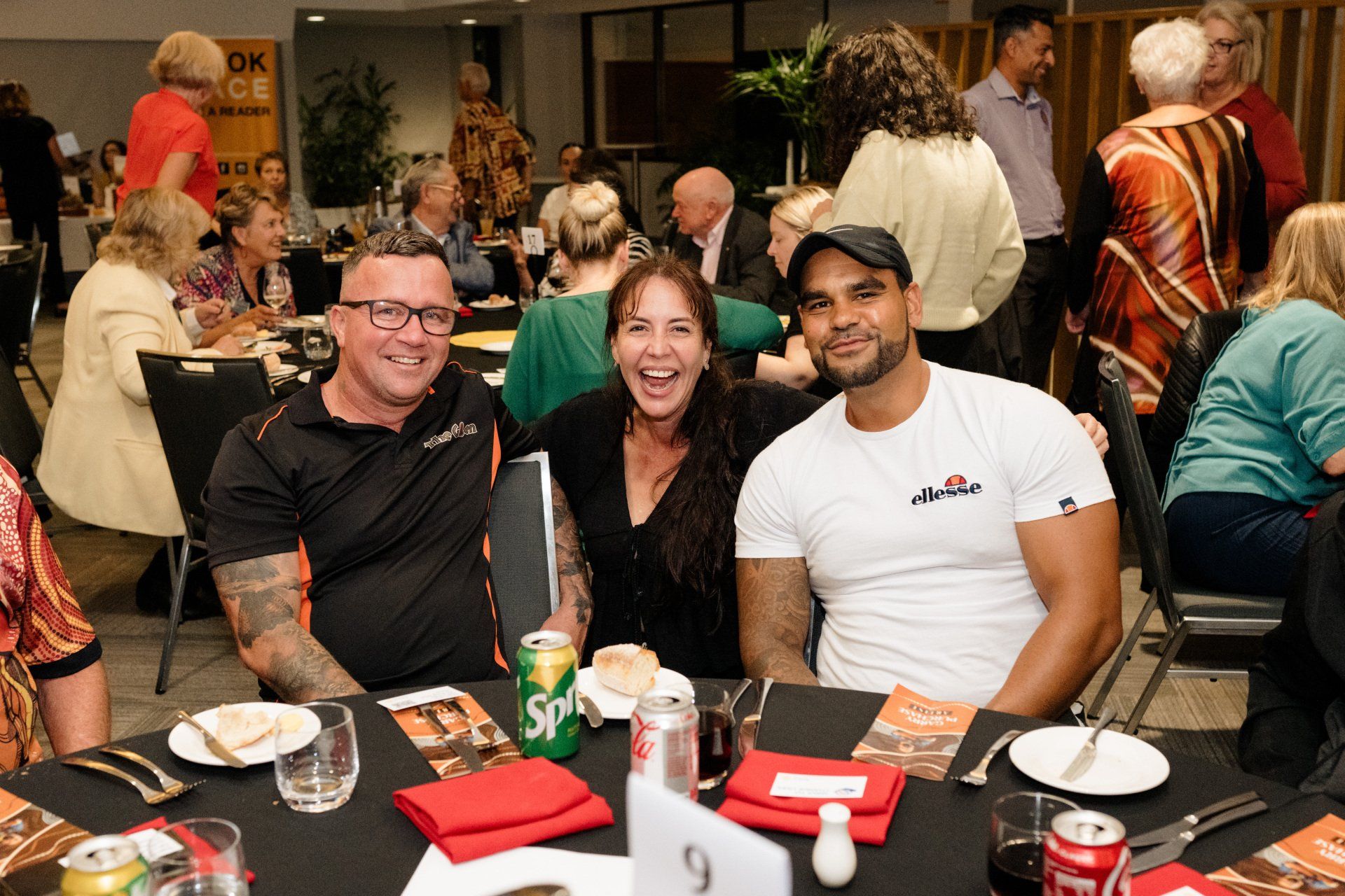 Three people are sitting at a table with a can of sprite on it.