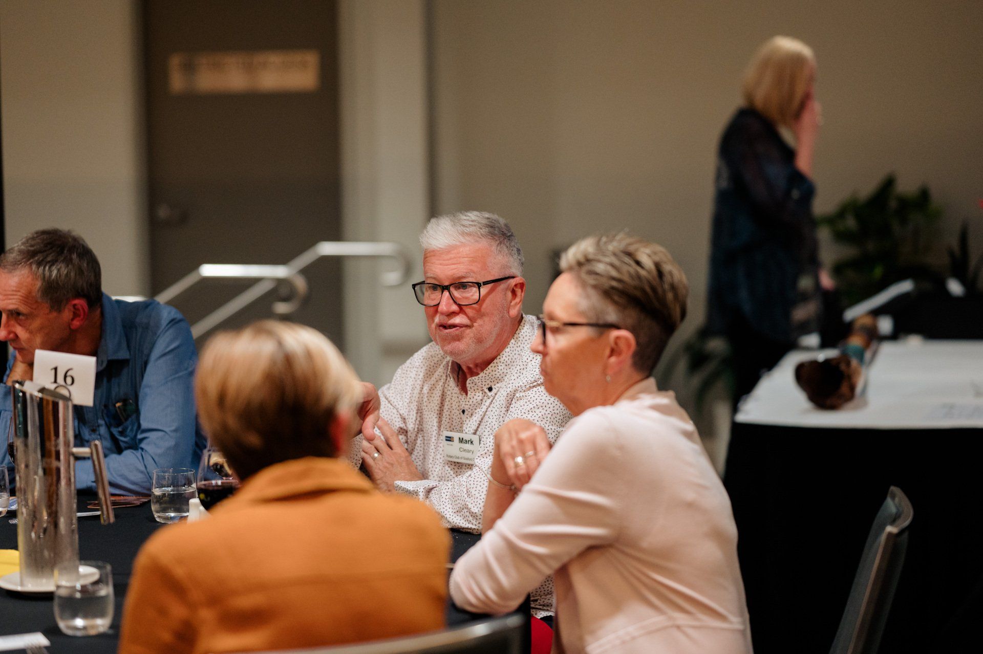 A group of people are sitting at a table talking to each other.