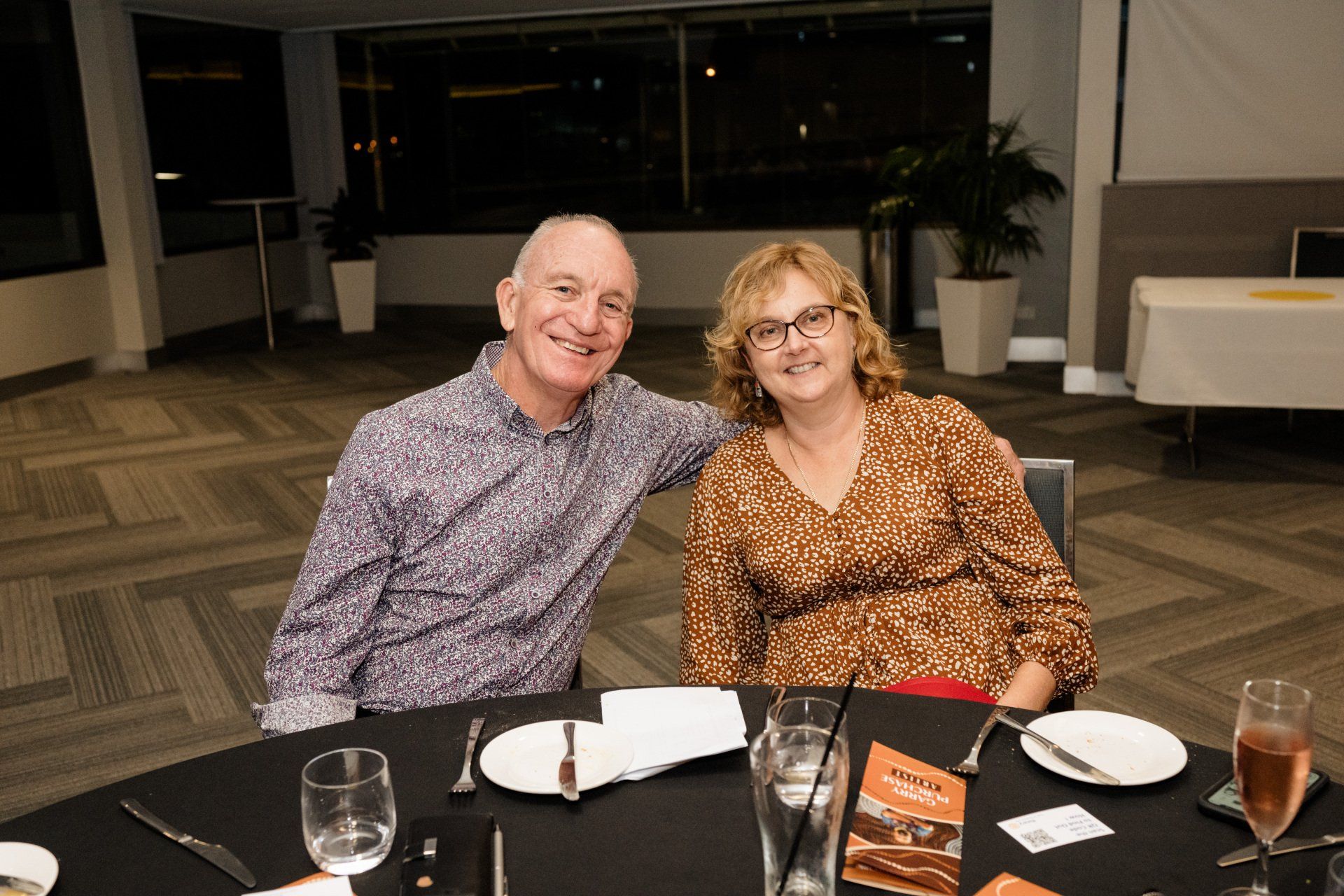 A man and a woman are posing for a picture at a table.