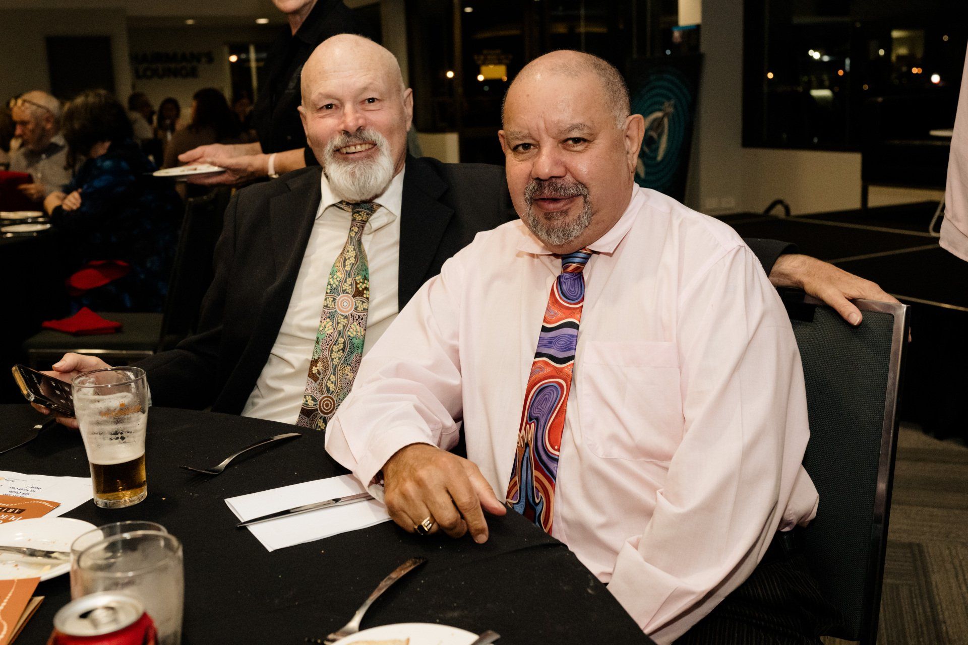 Two men are sitting at a table with a can of beer on it