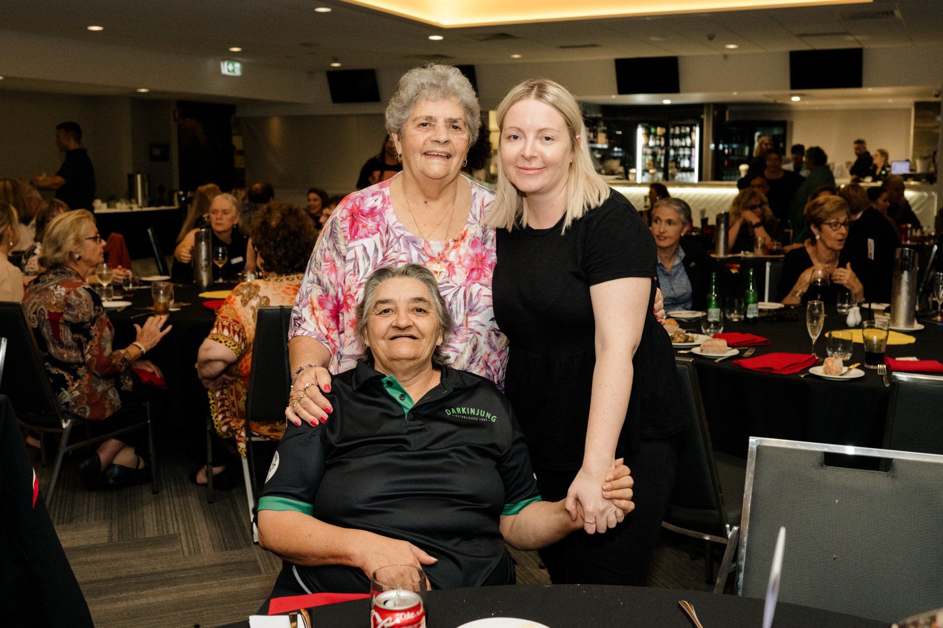 Three women are posing for a picture with a man in a wheelchair.