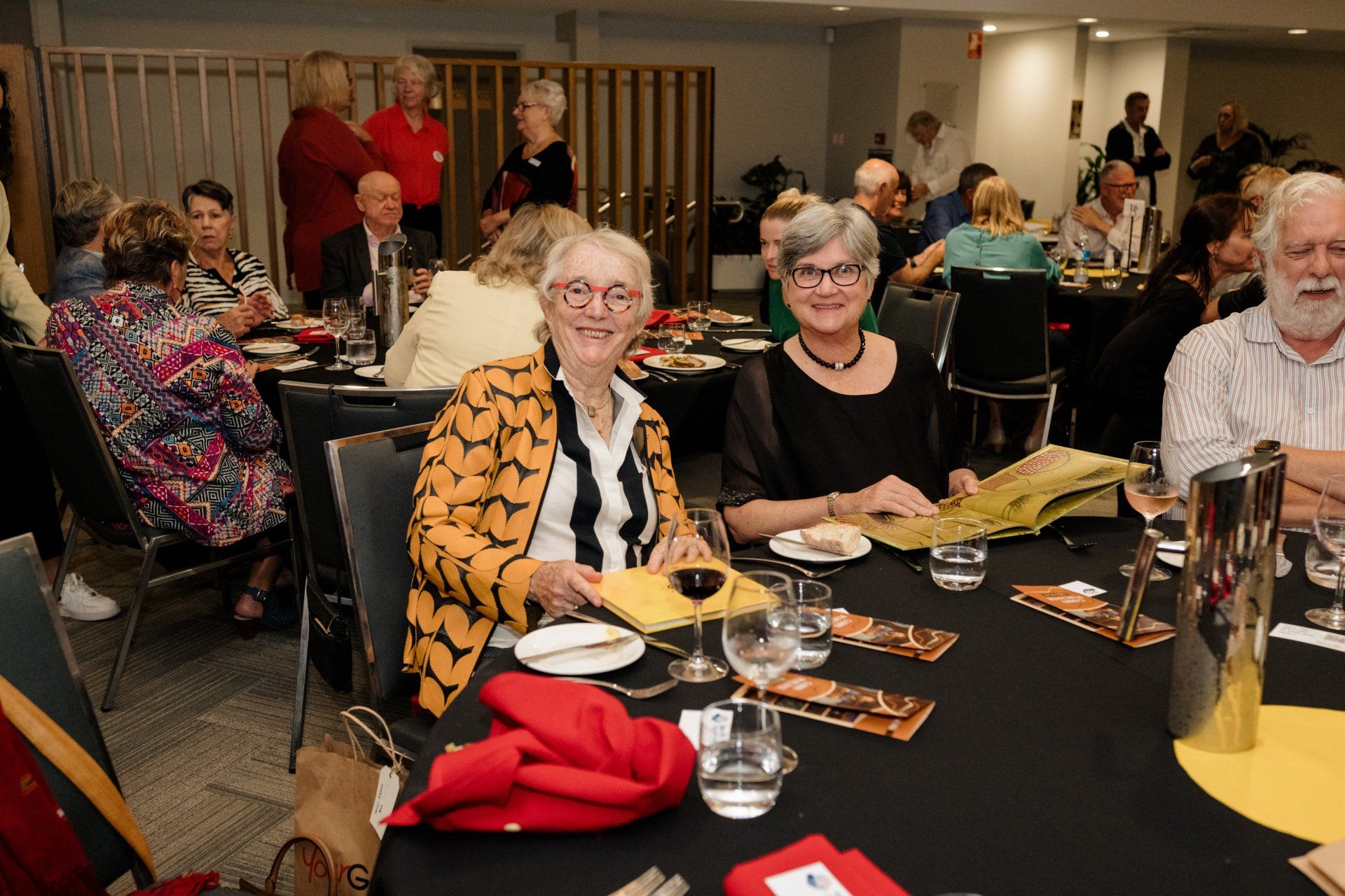 A group of people are sitting at a table with plates and glasses of wine.