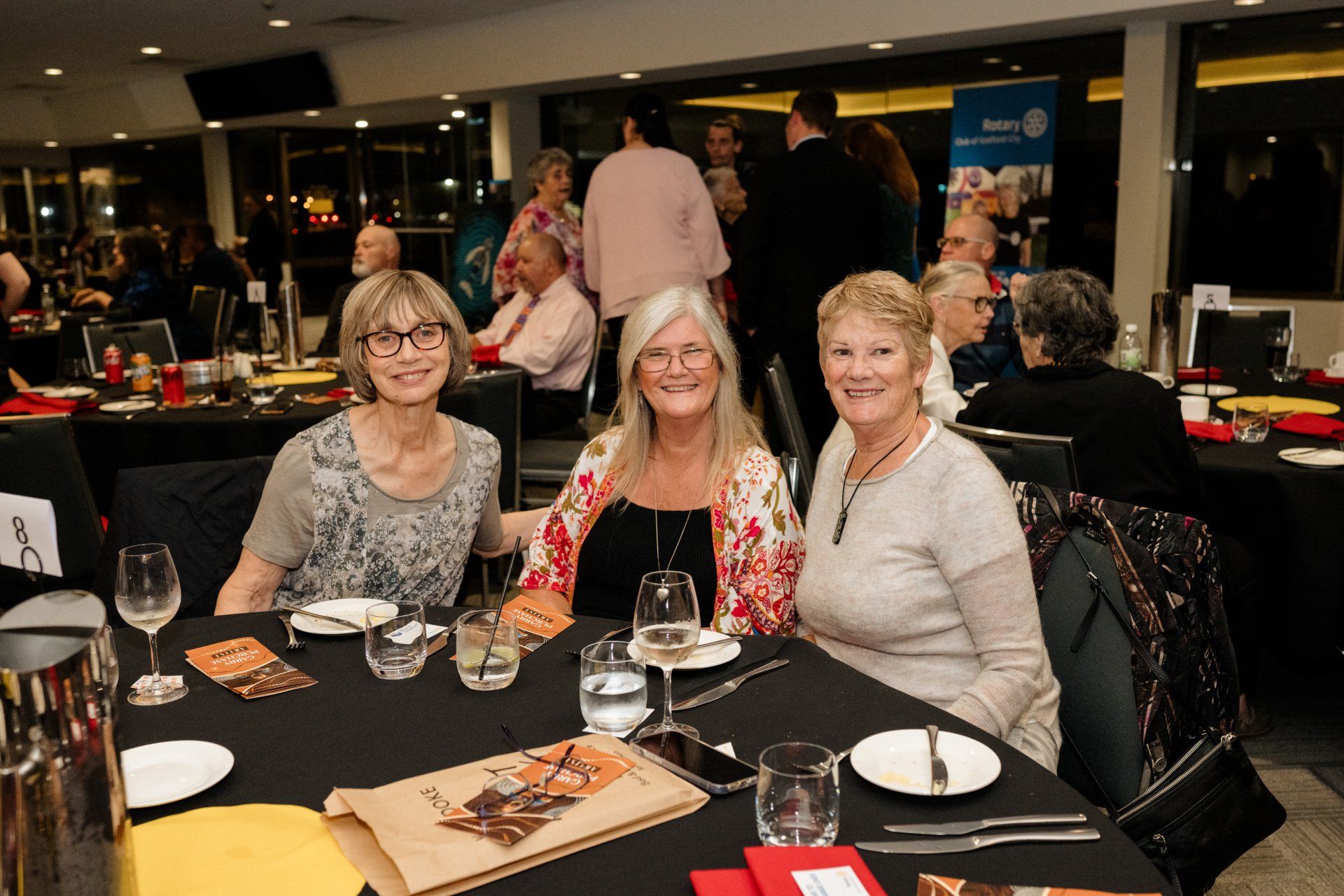 Three women are sitting at a table with plates and glasses of water.