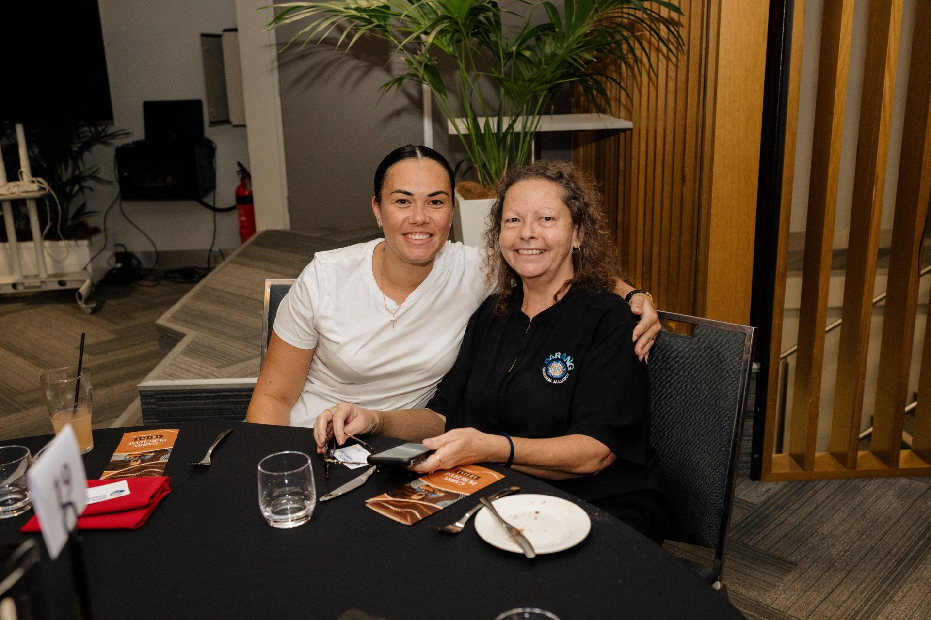 Two women are sitting at a table posing for a picture.