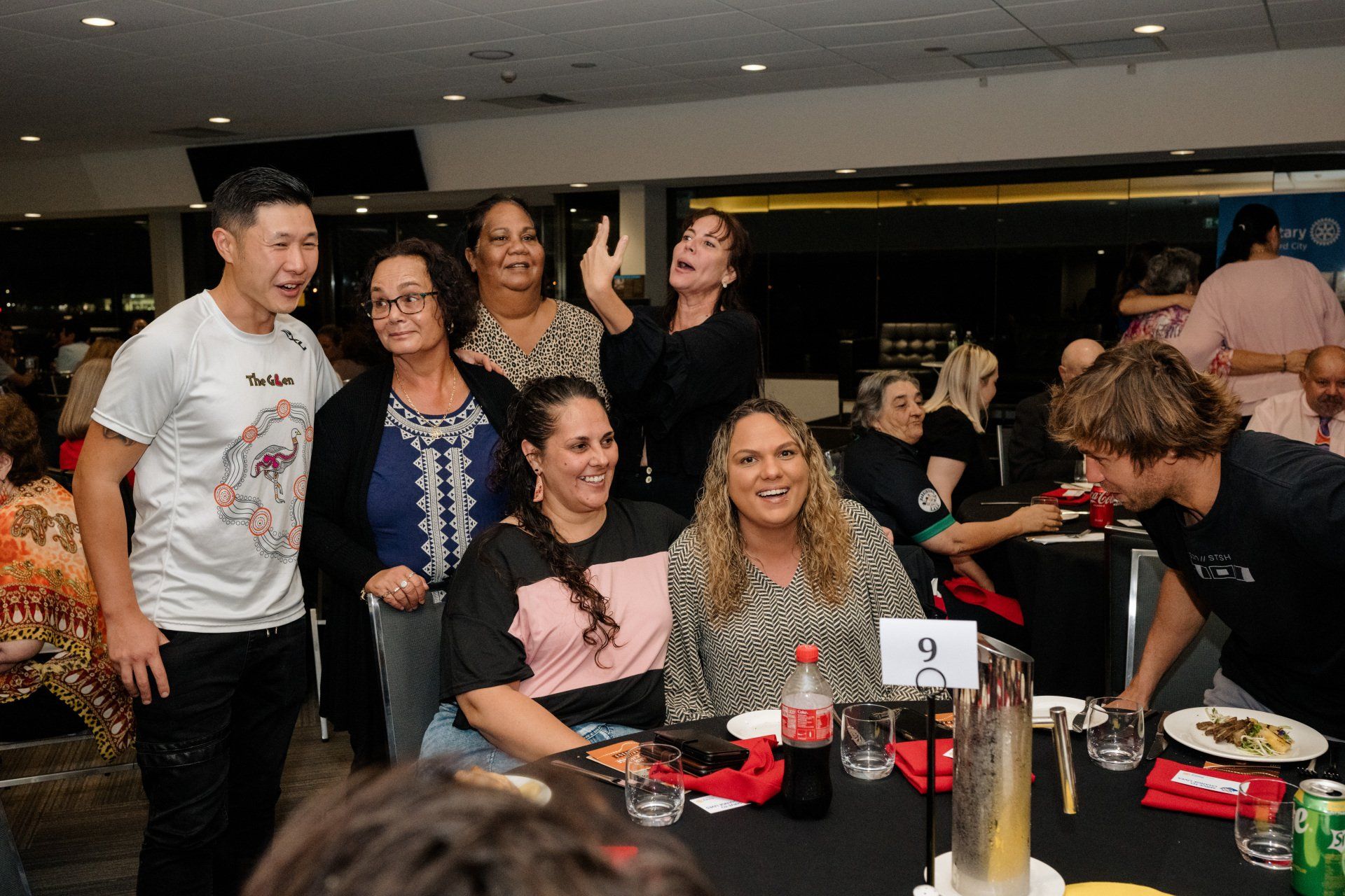 A group of people are posing for a picture while sitting at a table.