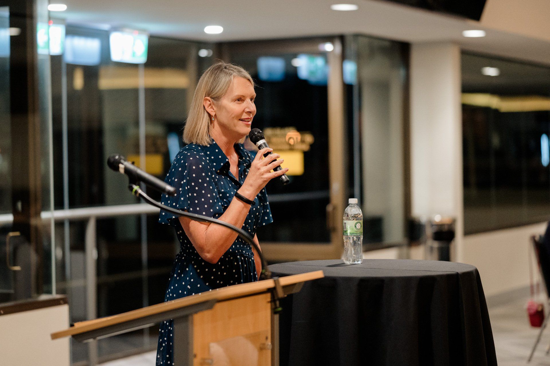 A woman is standing at a podium speaking into a microphone.