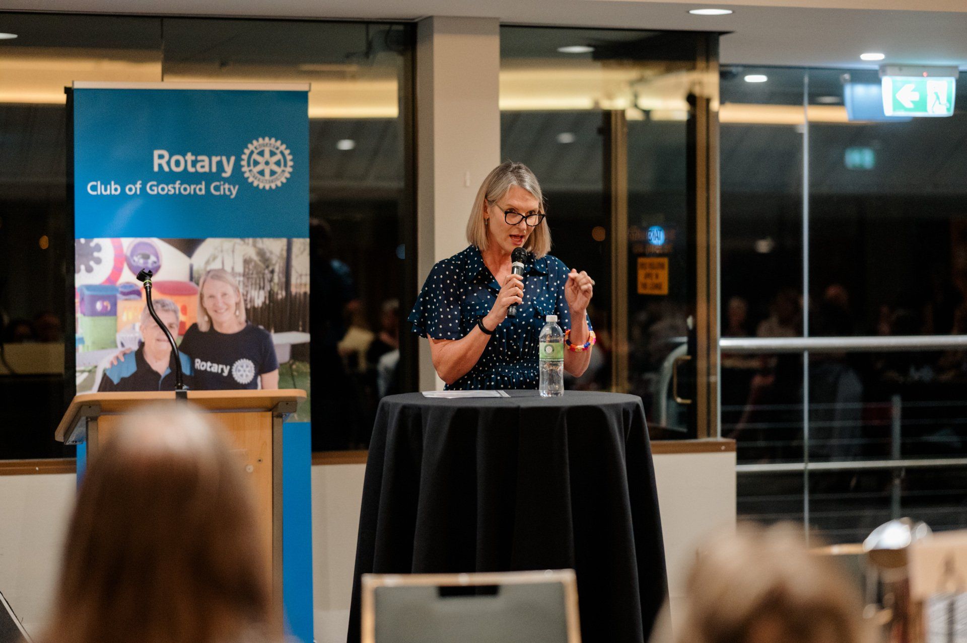A woman is standing at a podium talking into a microphone.