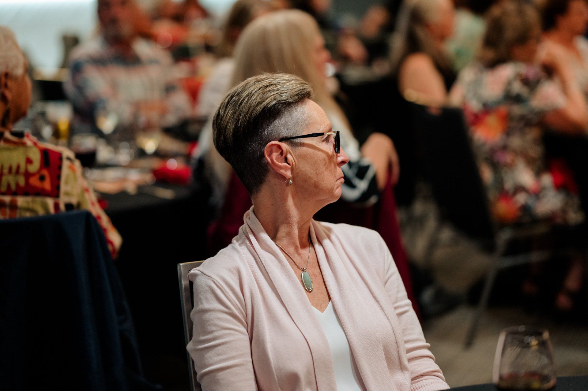 A woman is sitting at a table in a crowded room.