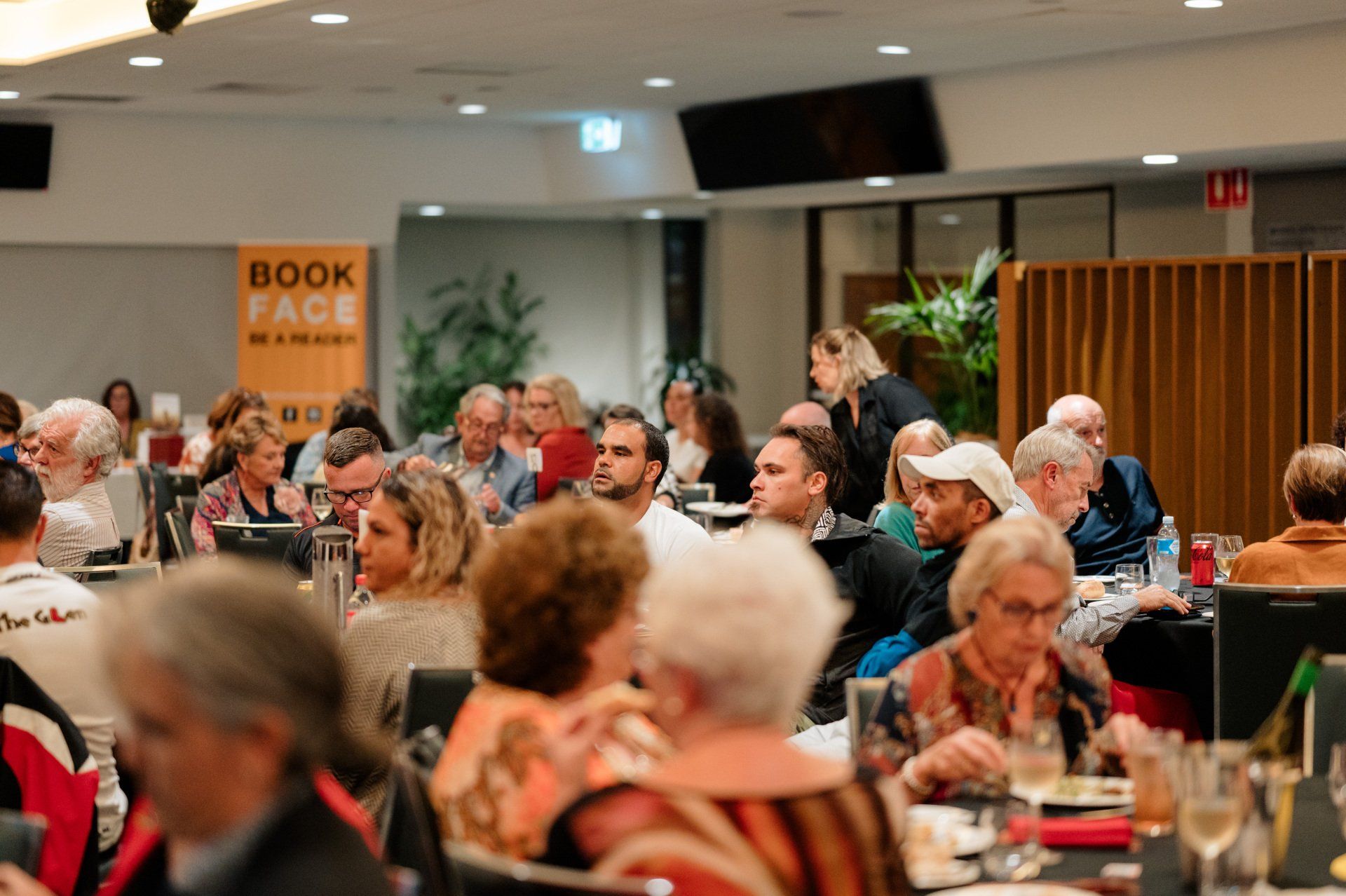 A large group of people are sitting at tables in a restaurant.