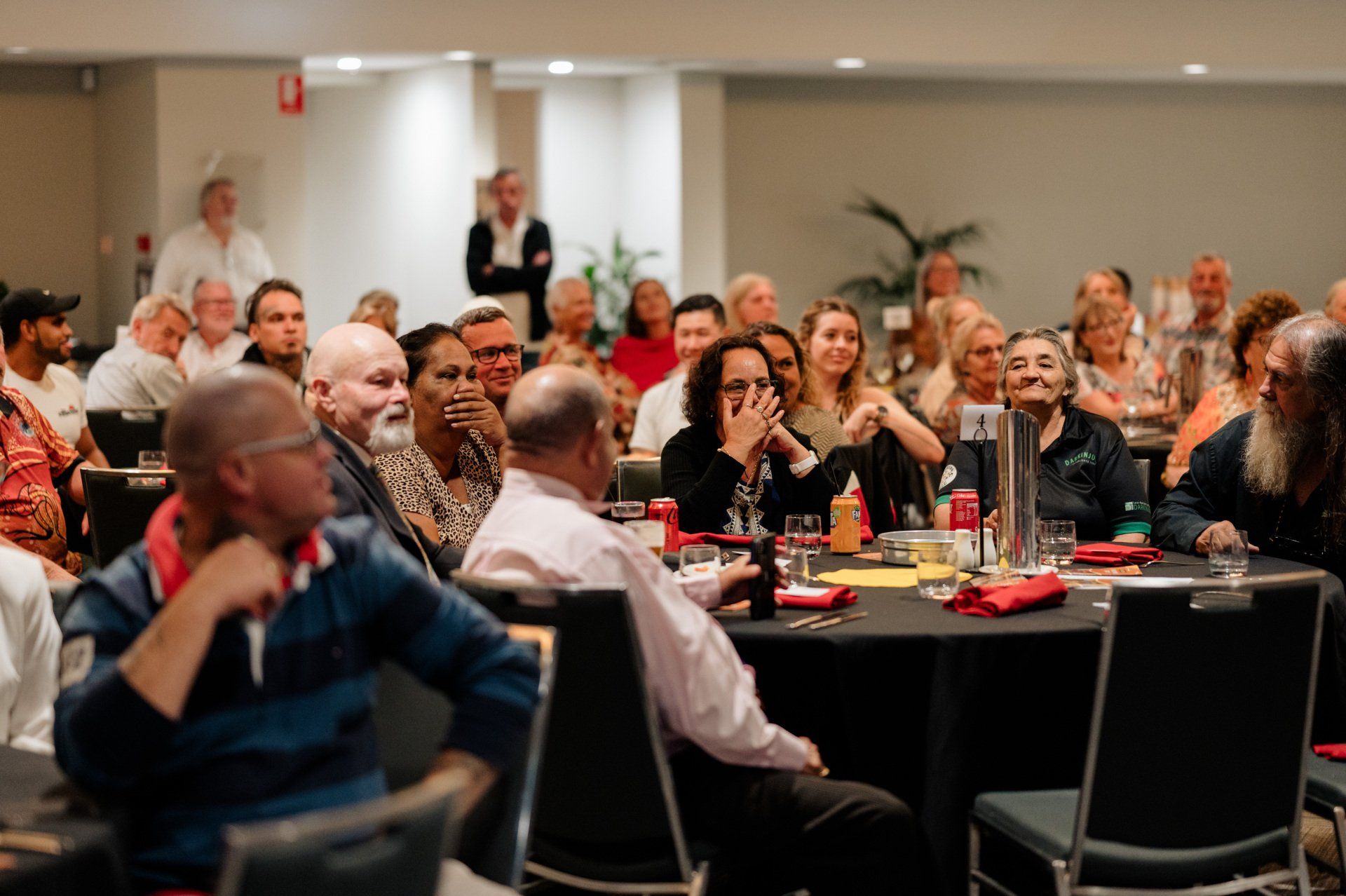 A large group of people are sitting at tables in a room.