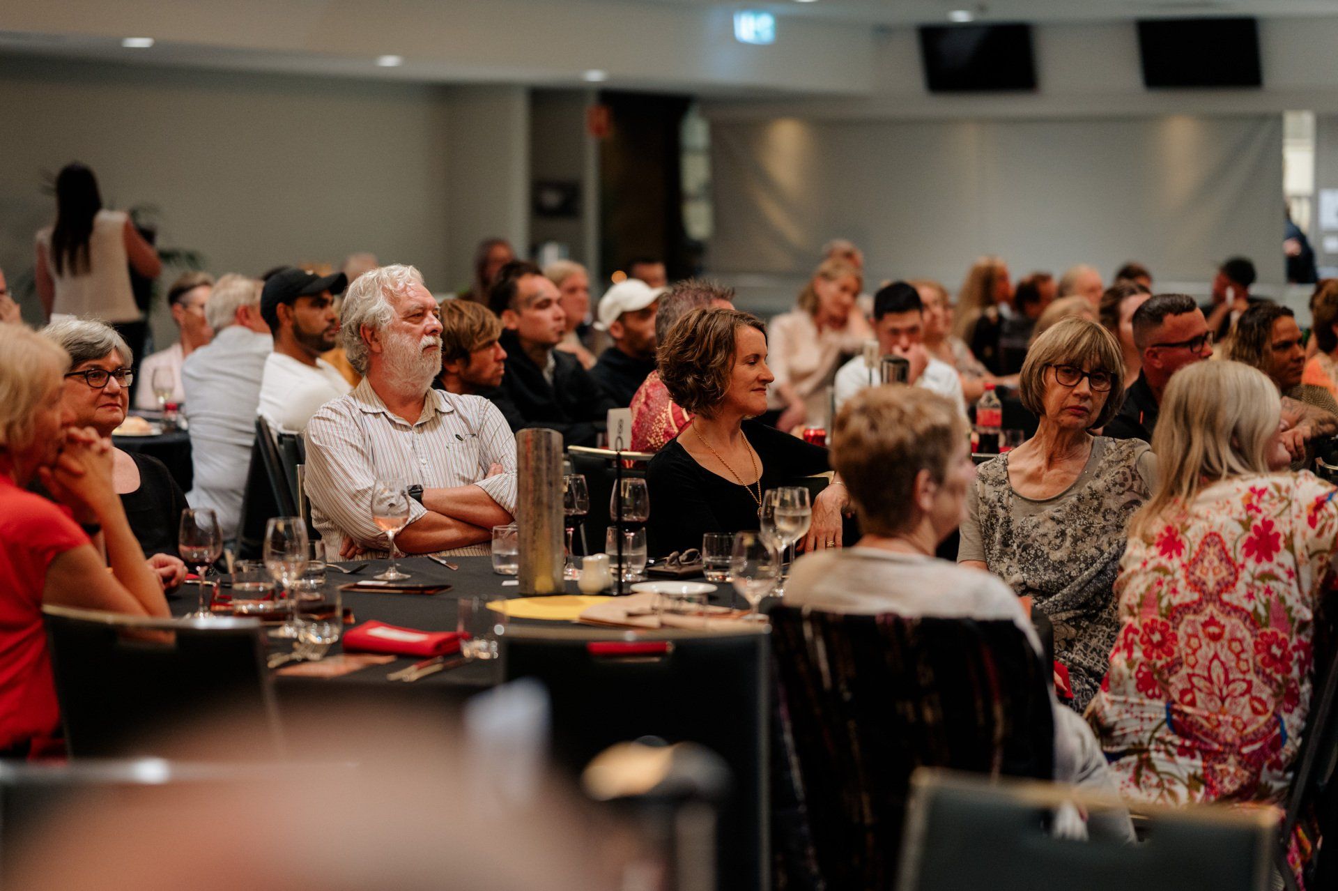 A large group of people are sitting at tables in a room.
