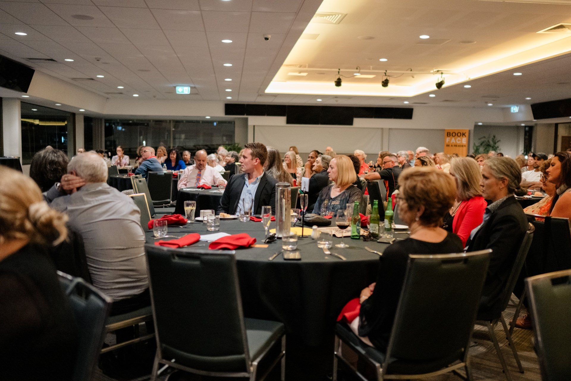 A large group of people are sitting at tables in a large room.