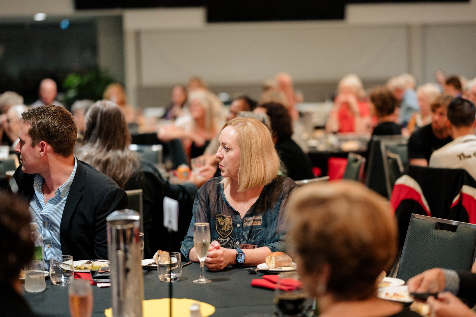 A group of people are sitting at tables at a dinner party.