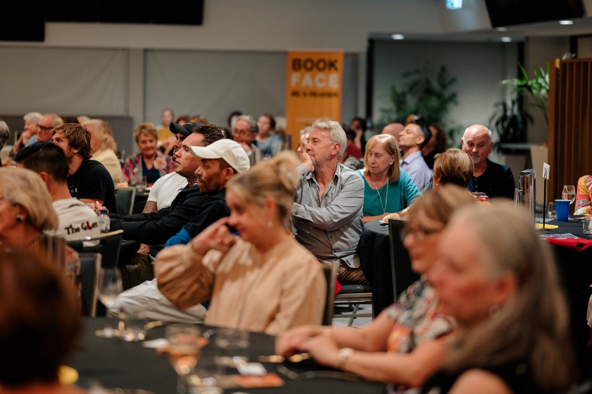 A large group of people are sitting at tables in a room.