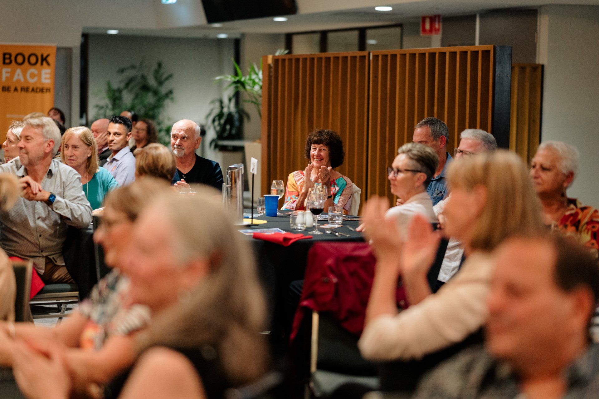 A group of people are sitting in a room clapping their hands.