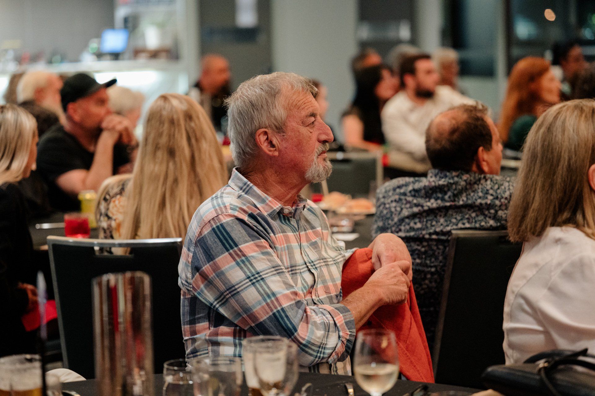 A man is sitting at a table in a restaurant with a group of people.