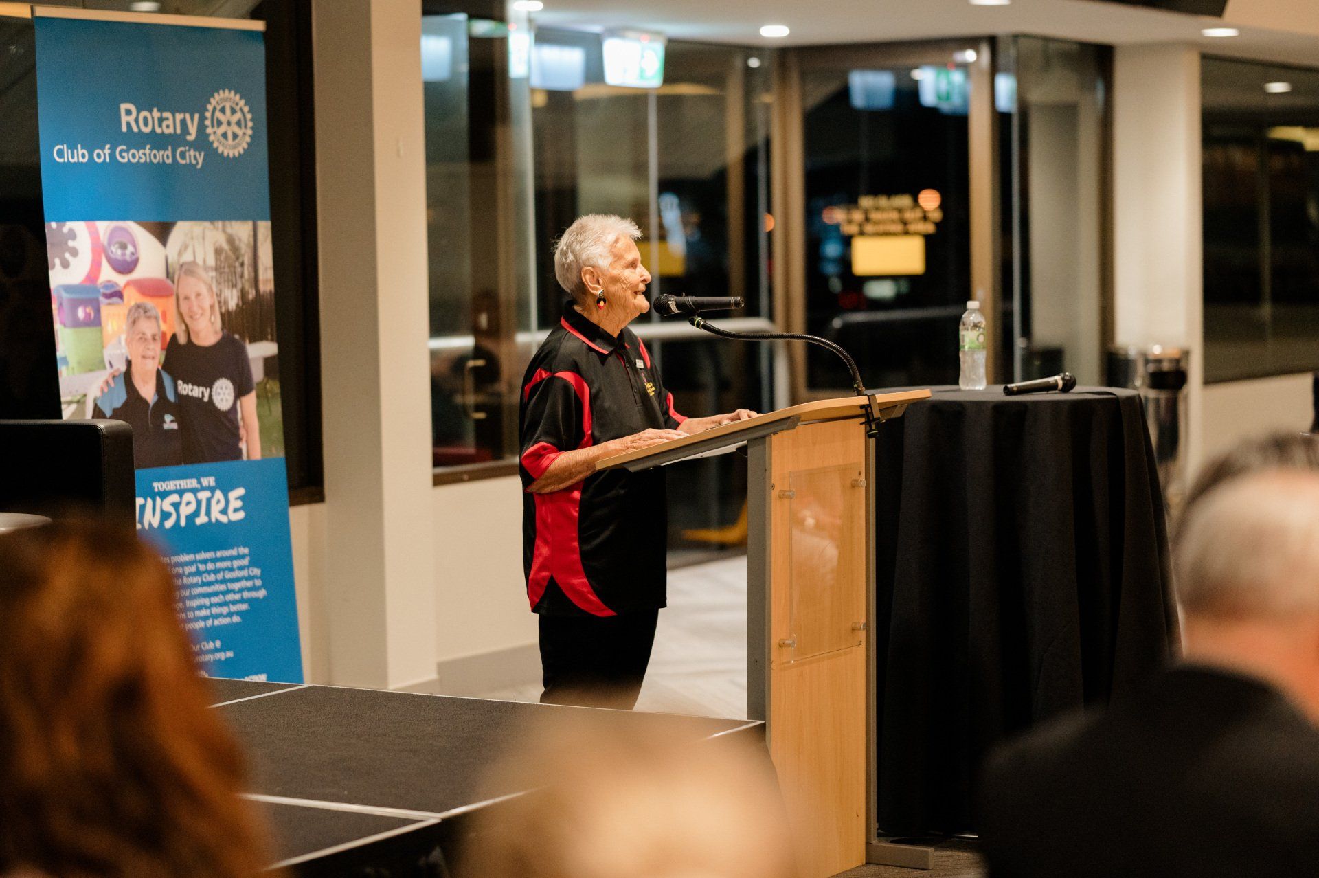 A woman is standing at a podium speaking into a microphone.