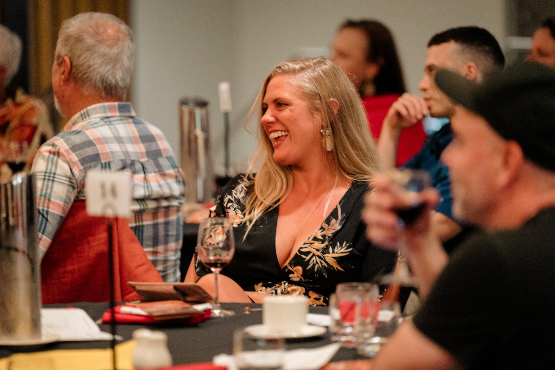 A woman is sitting at a table with a glass of wine.