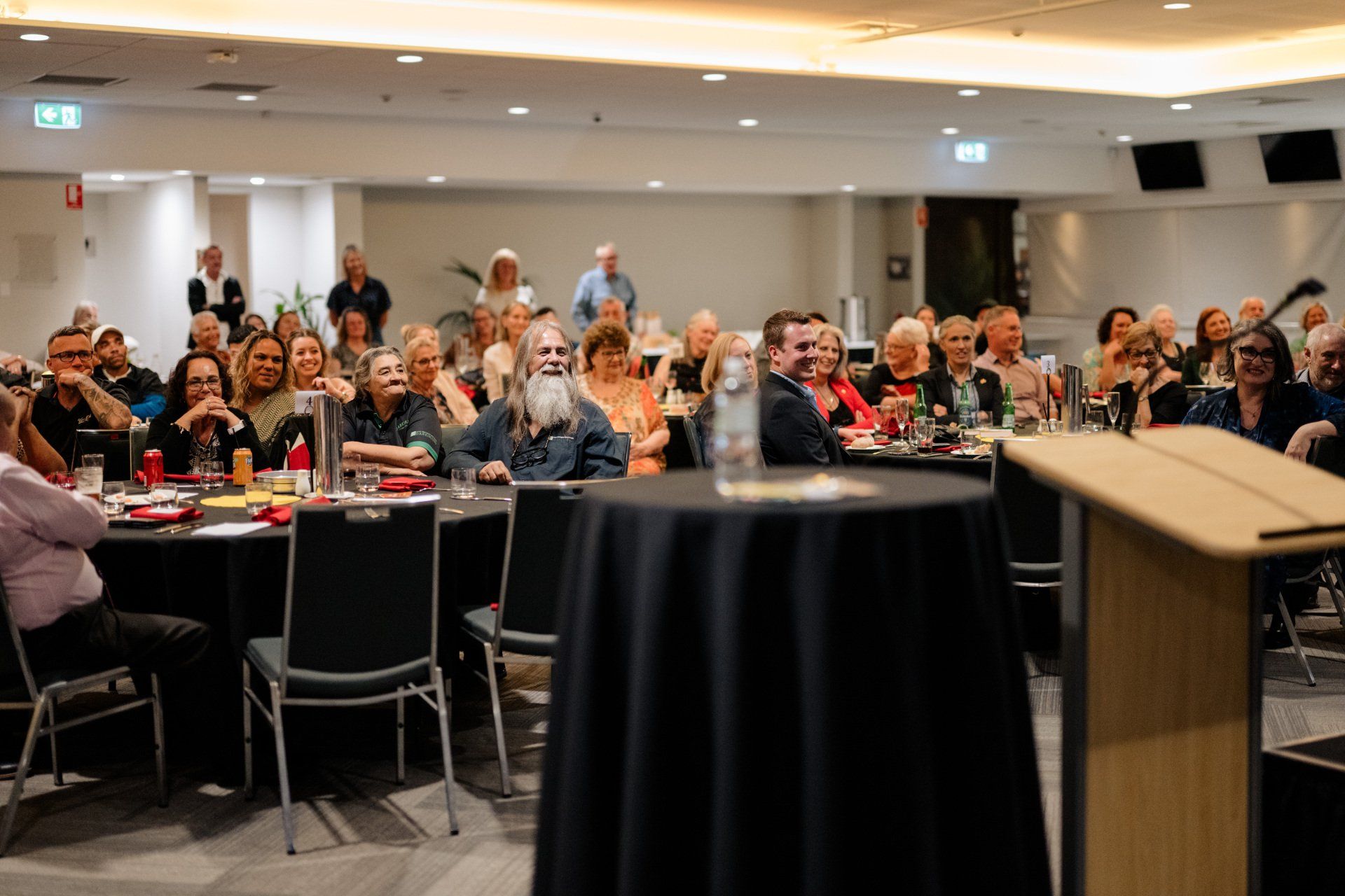 A large group of people are sitting at tables in a conference room.